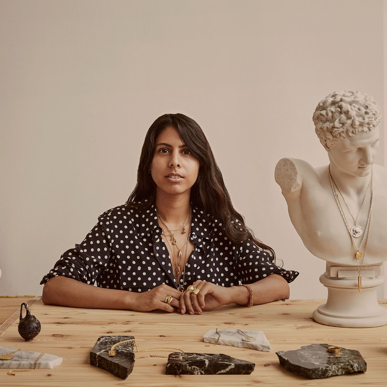 woman with jewellery in front of her and bust statue next to her