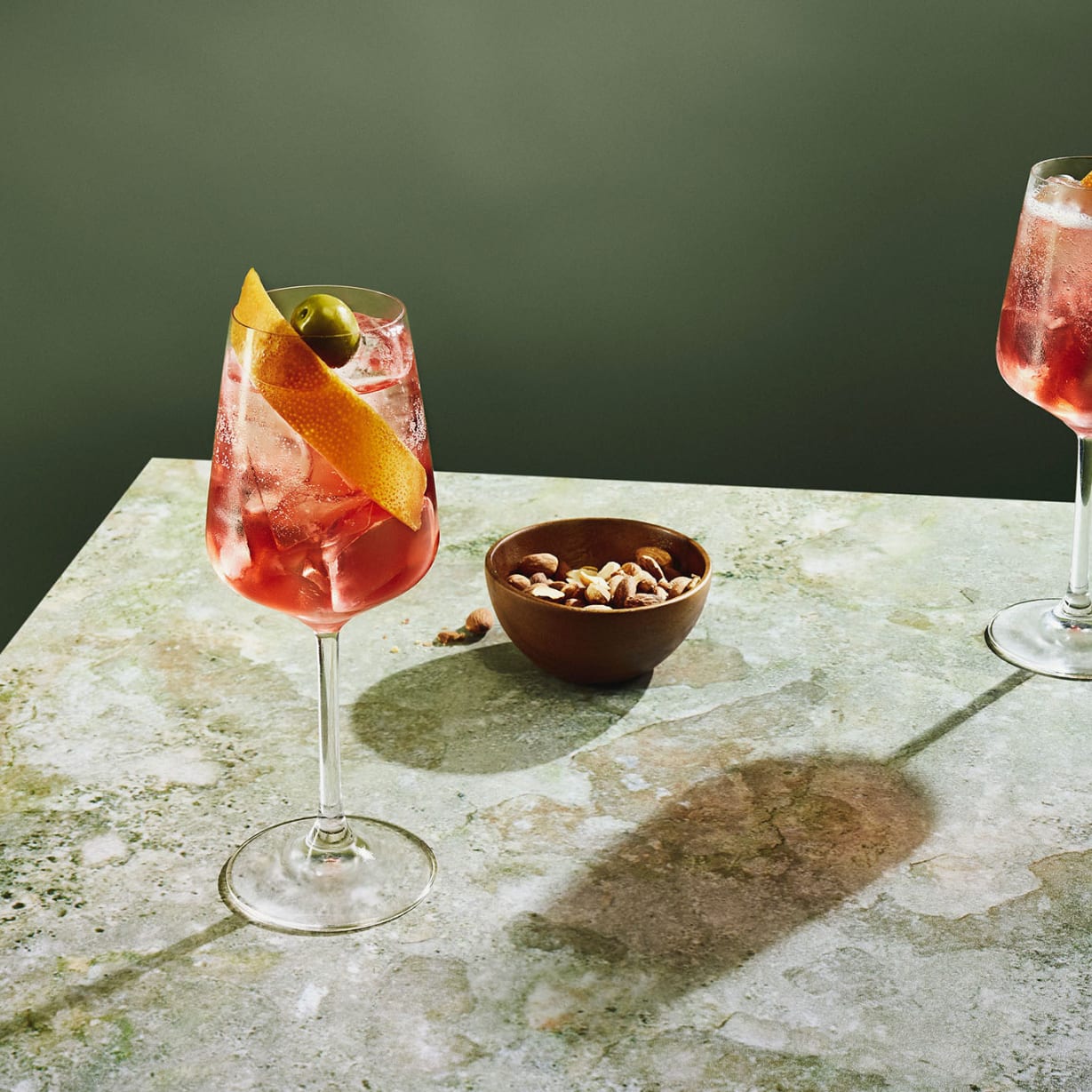 Two glasses with cocktails and bowl of olives