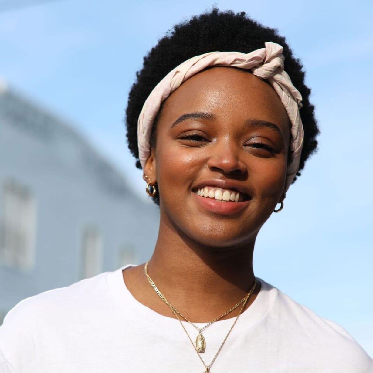 Woman in t-shirt and necklaces smiling at camera