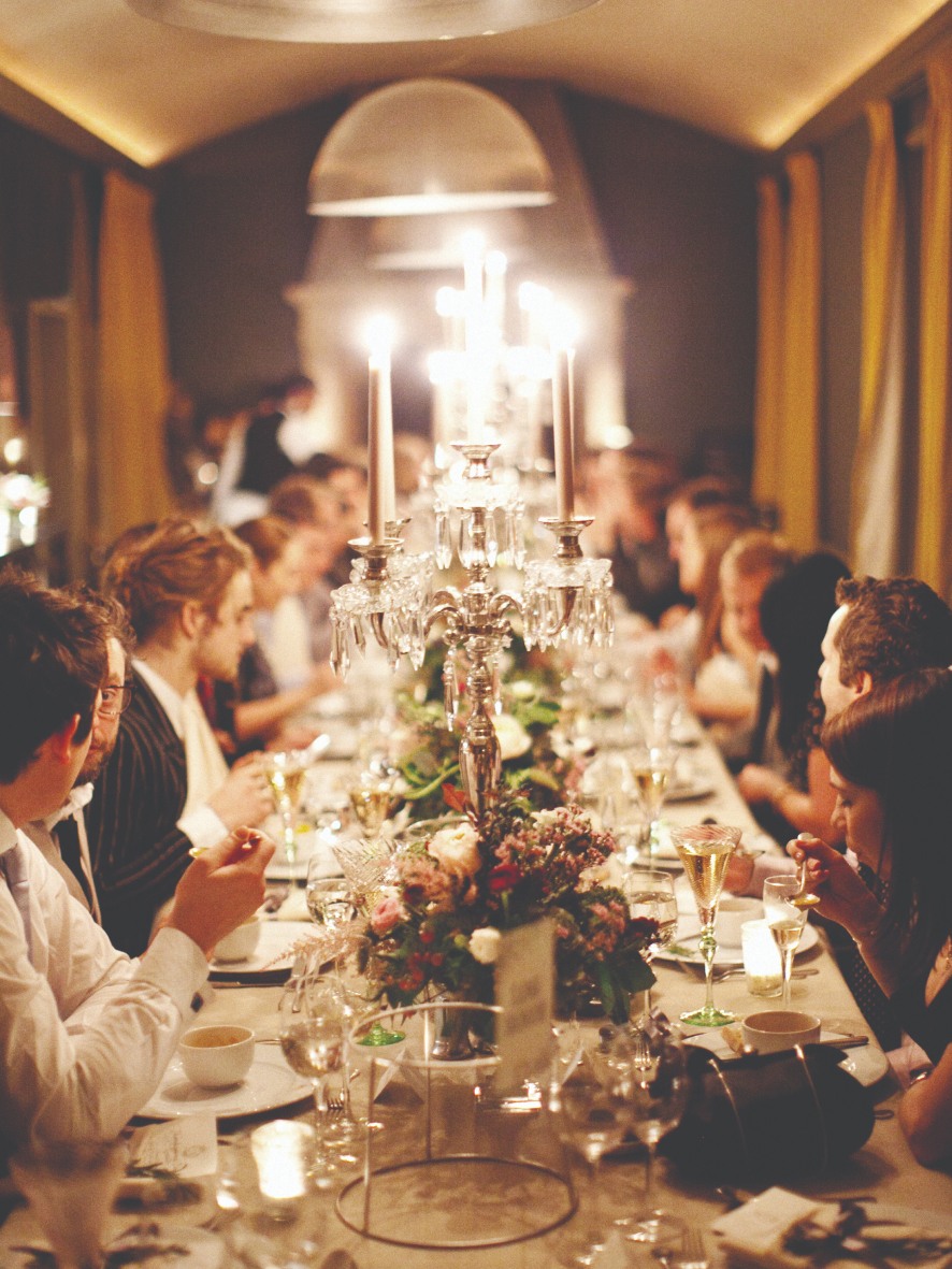 Wedding guests sat around a candle lit dinner table.