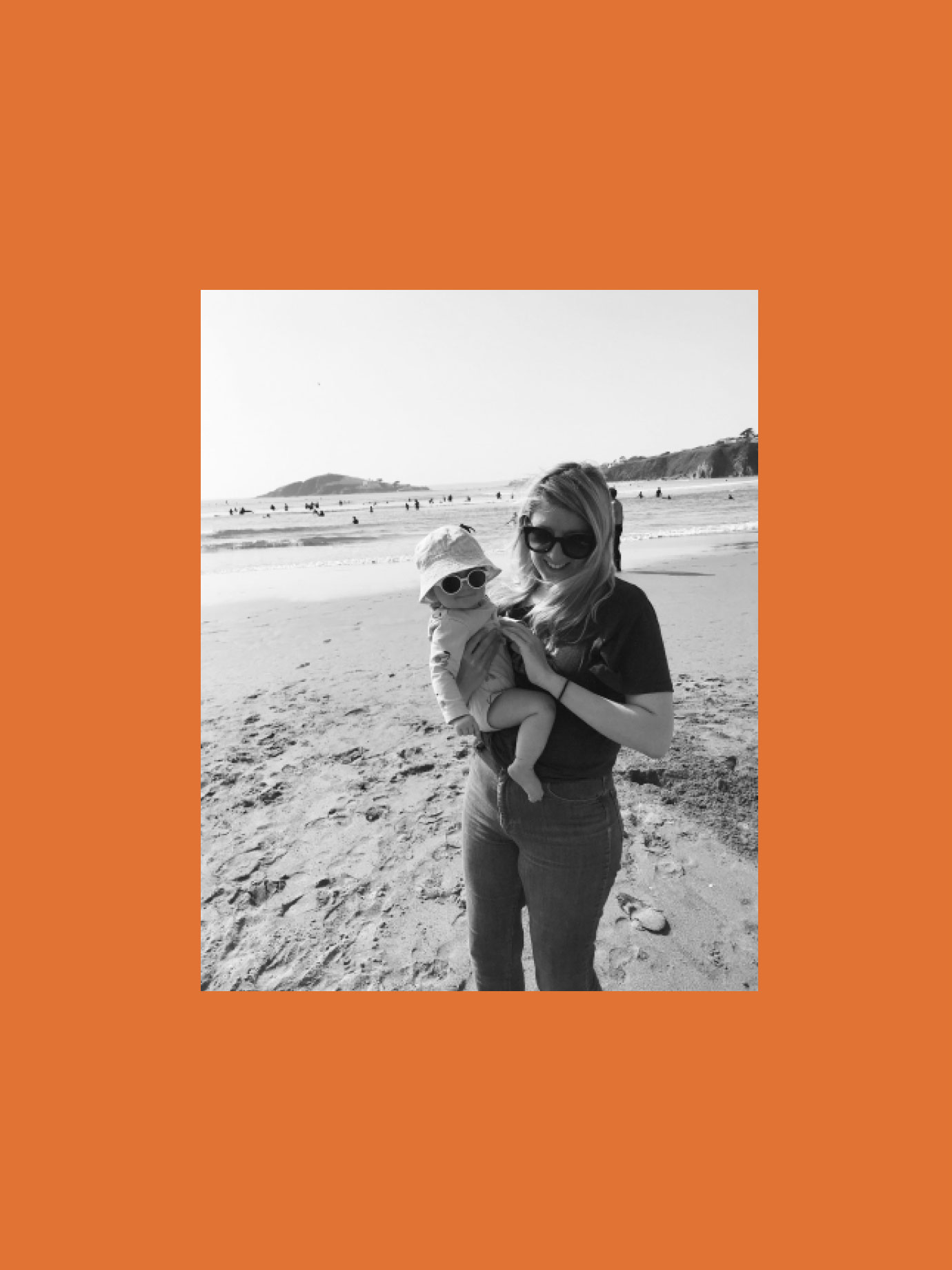 A woman holding a baby on the beach.