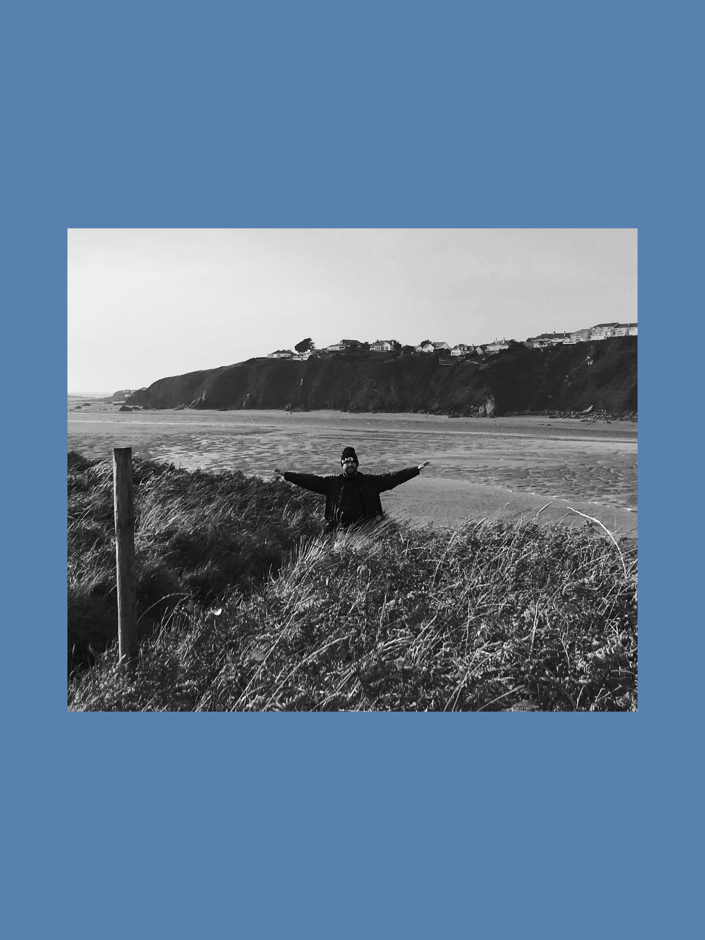 A man with his arms out wide by the sea.