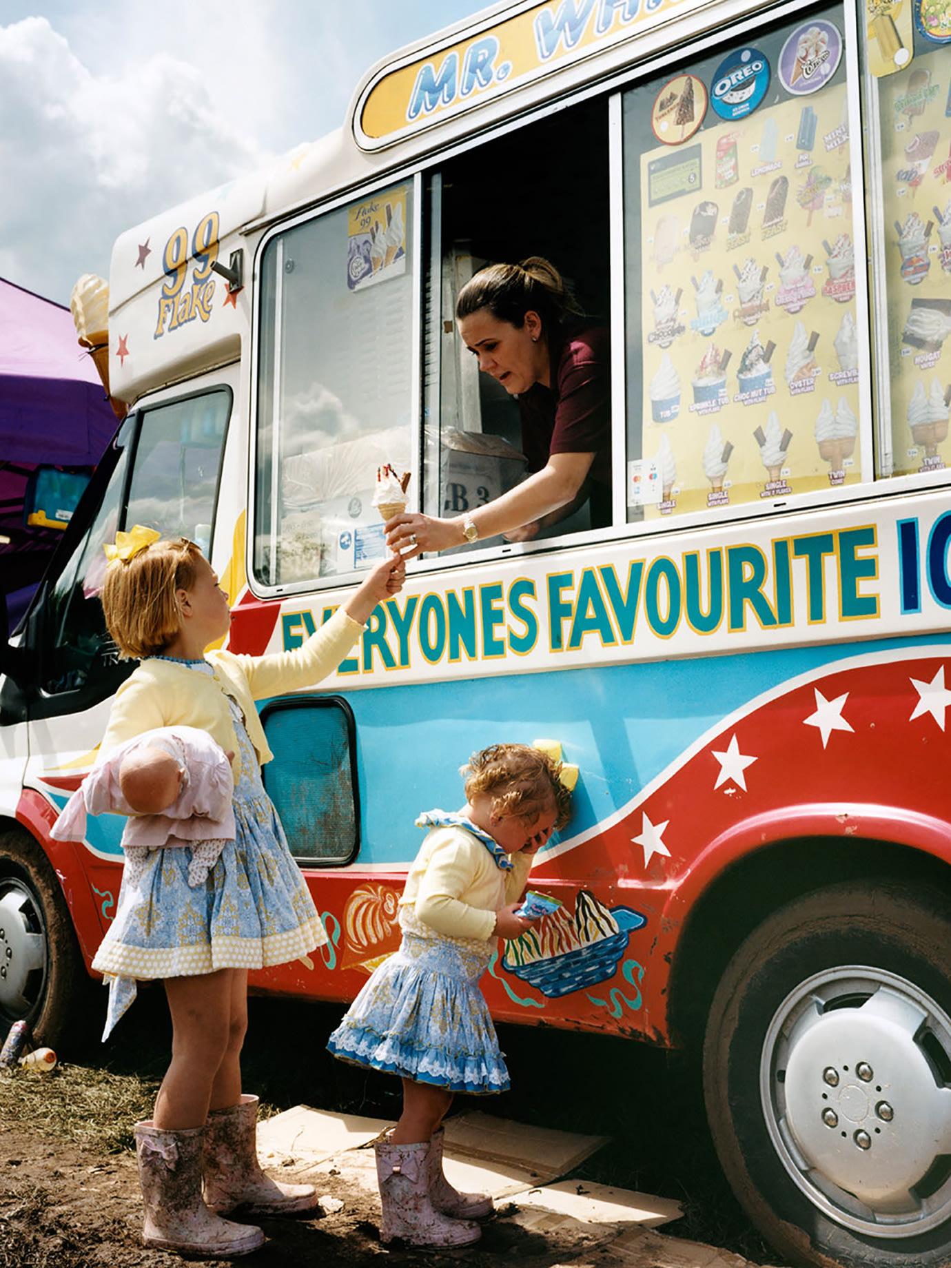Two children being served ice cream from a van.
