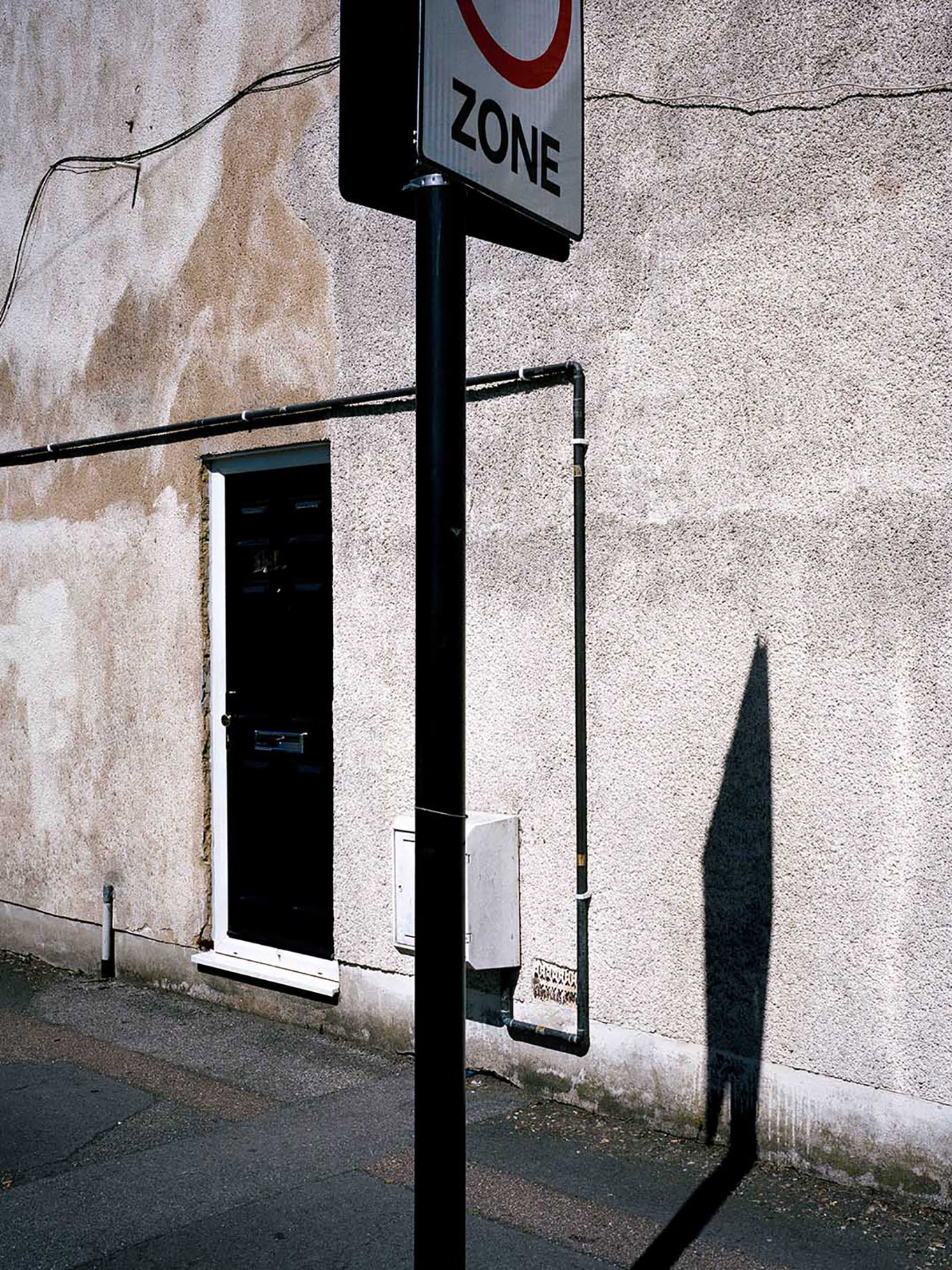 A street sign casting a shadow on a wall.