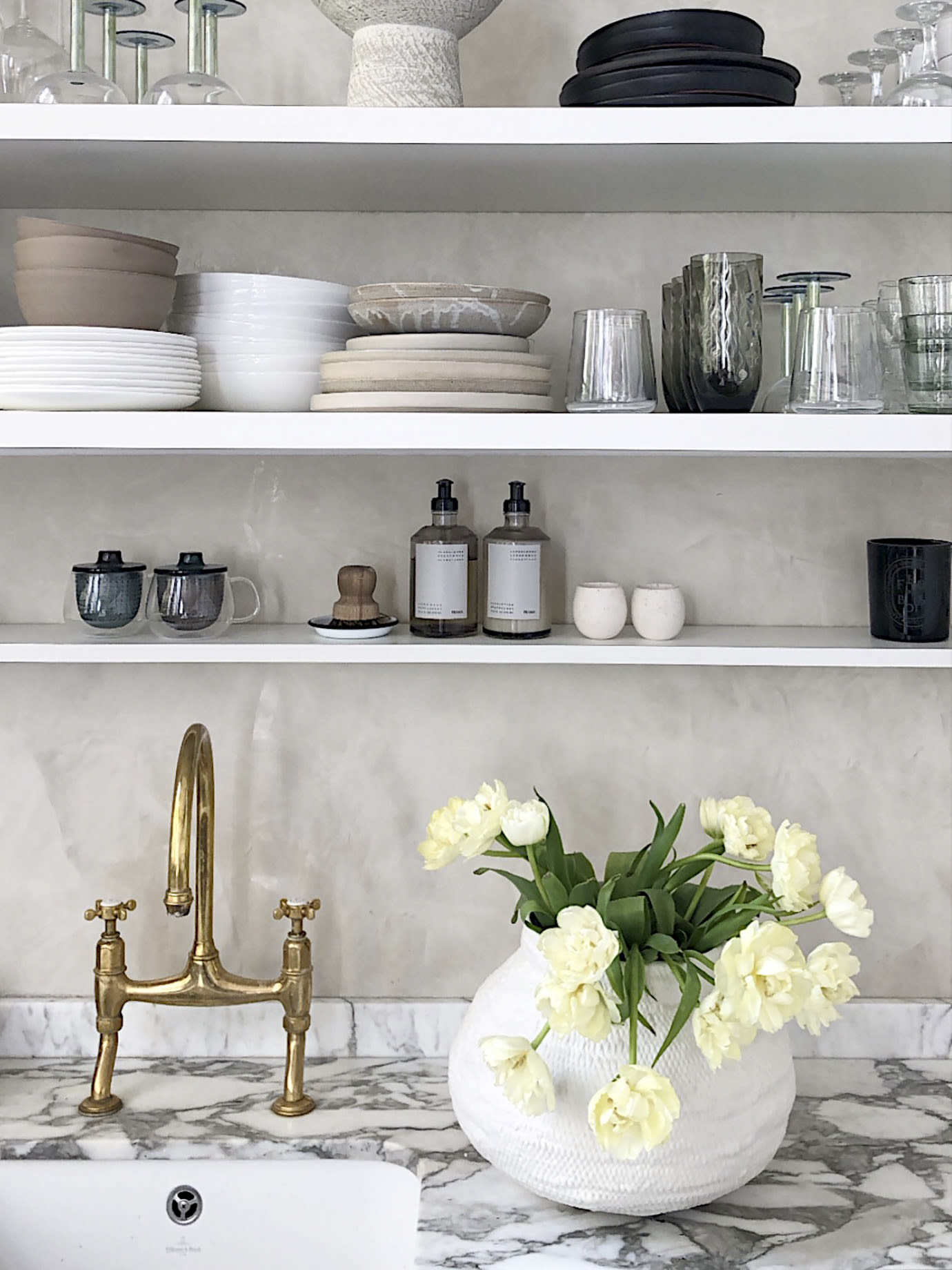 A sink underneath some shelves.