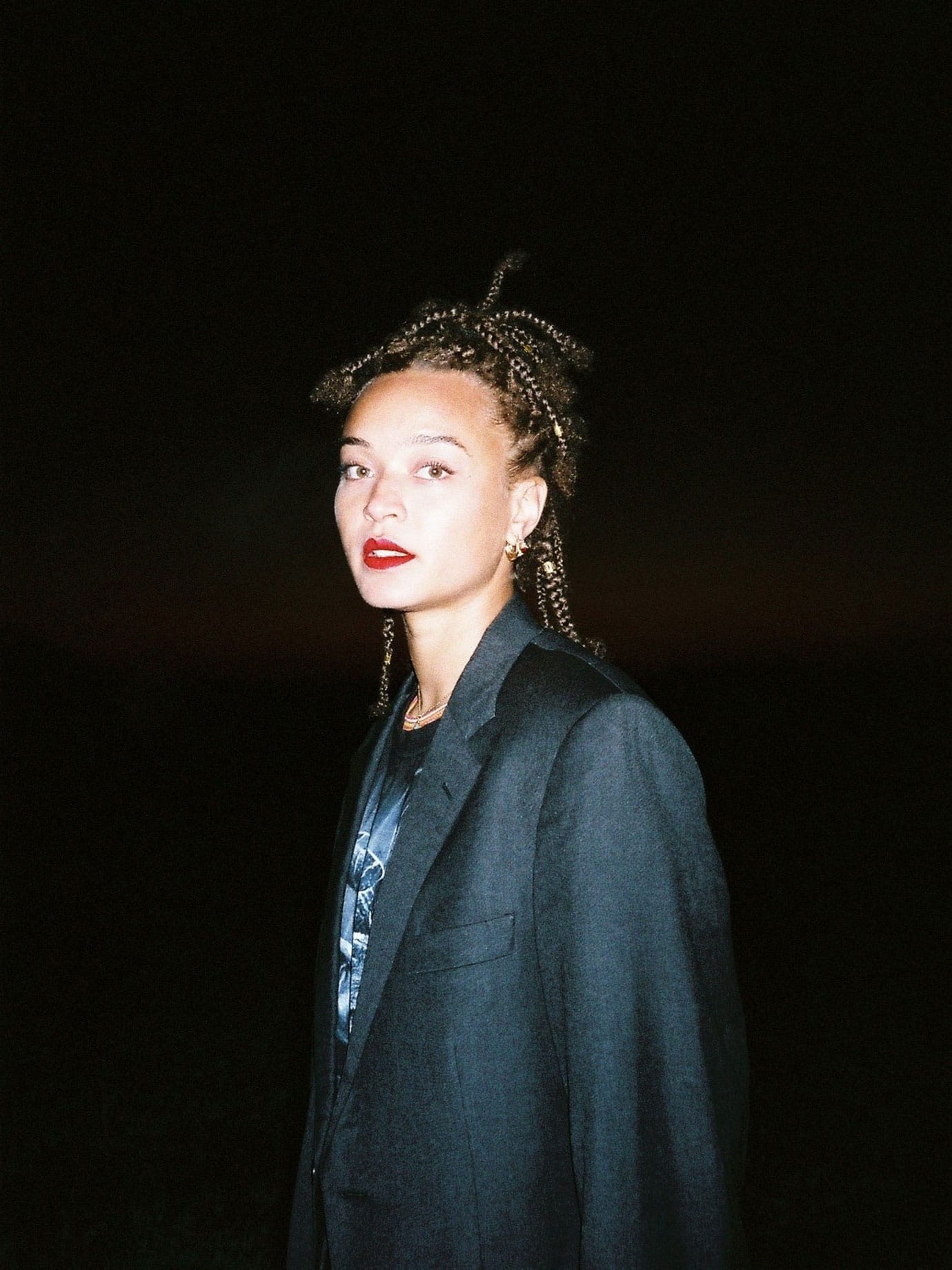 A woman wearing a suit jacket at night.