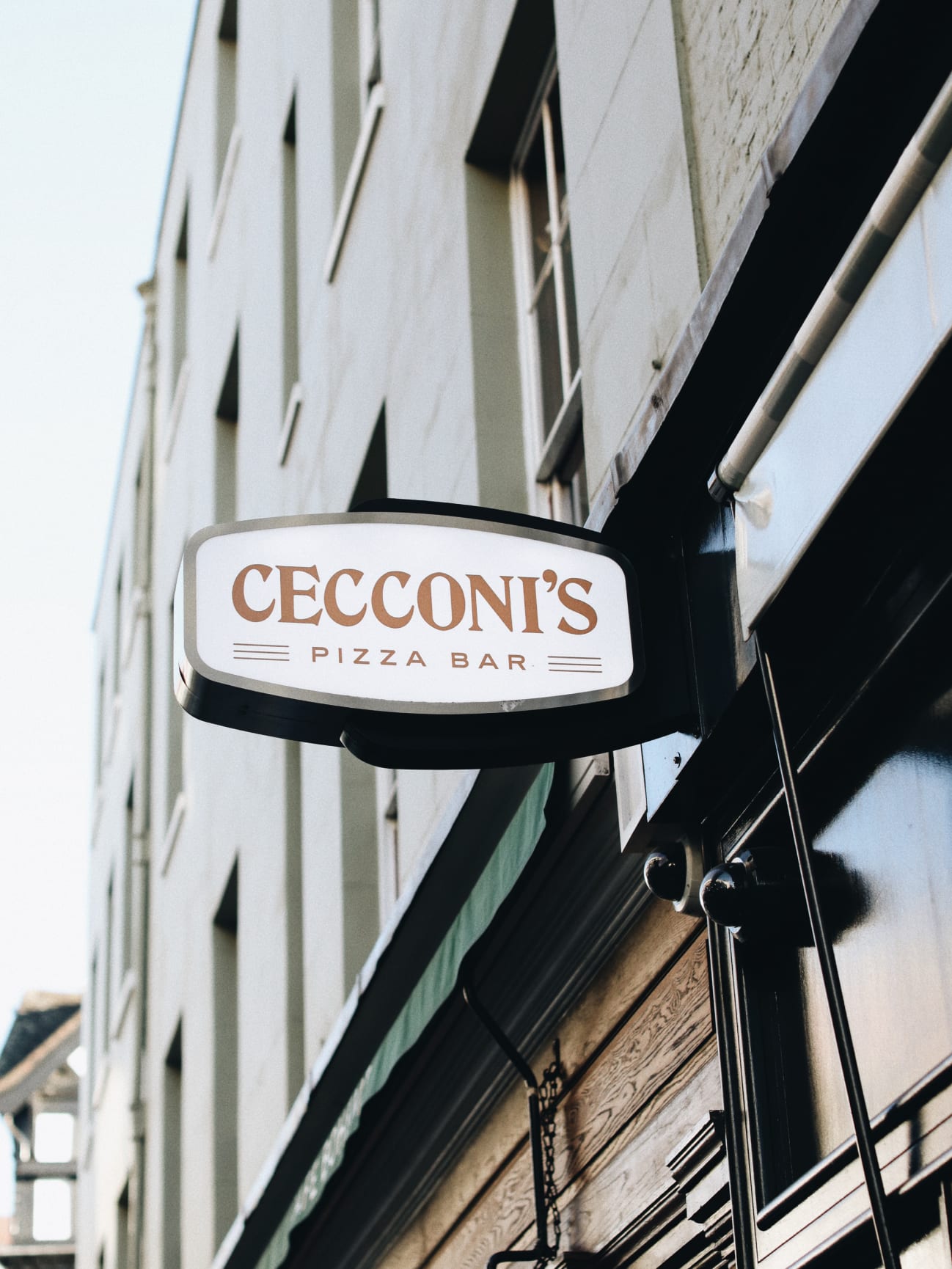 The exterior of a restaurant with a sign saying Cecconis Pizza Bar protruding from its wall.