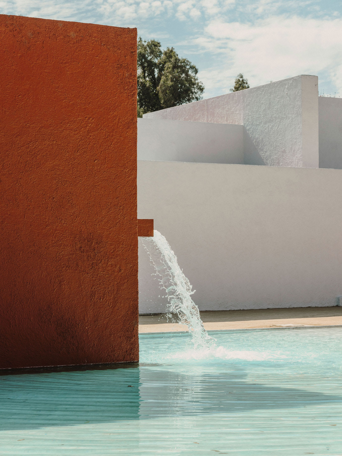 A pink and white outdoor area with a small water feature.