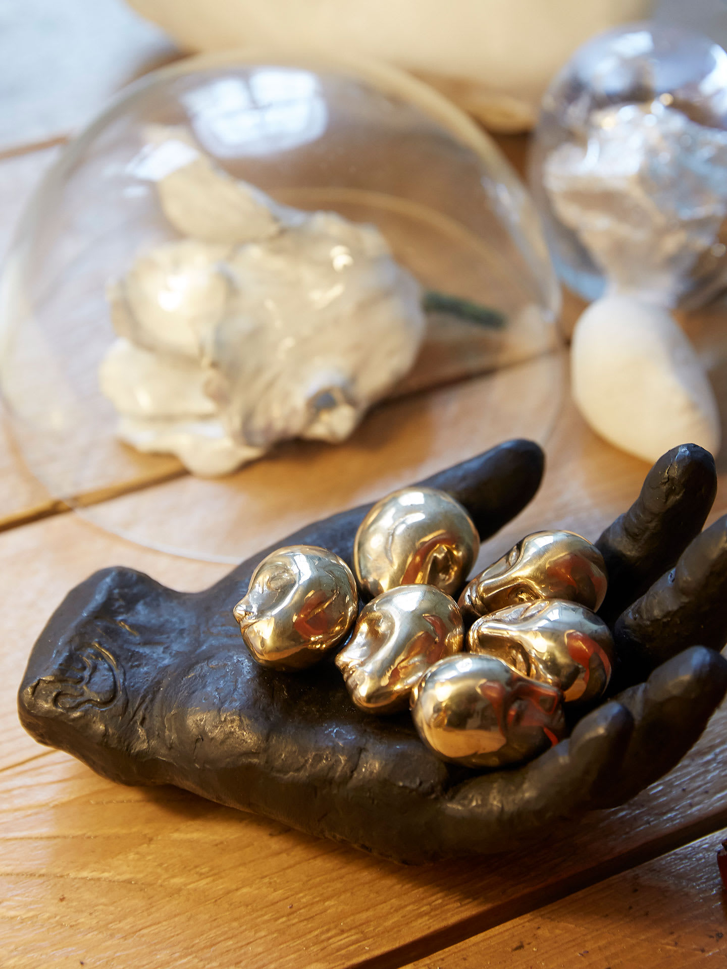 A sculpture of a black hand with six gold alien heads on it.
