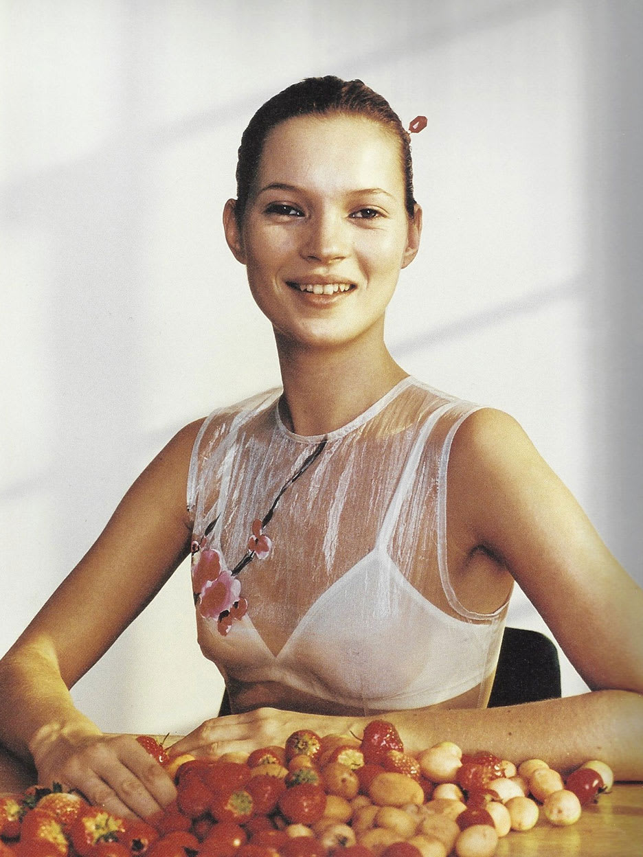 A woman posing in front of fruit.