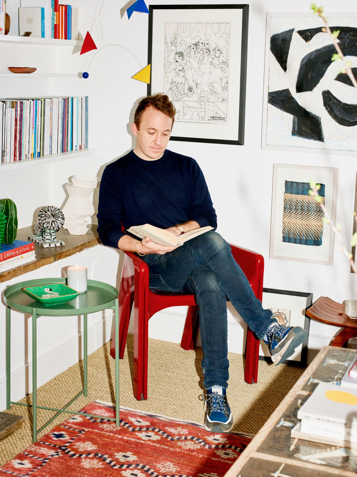 A man reading a book on a red chair.