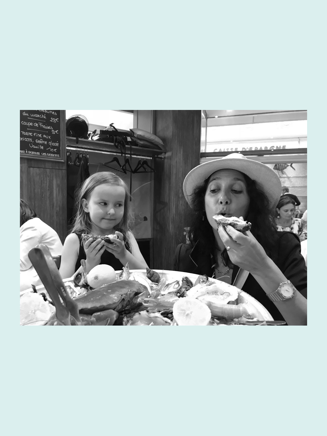 A woman and a young girl eating oysters in a restaurant.
