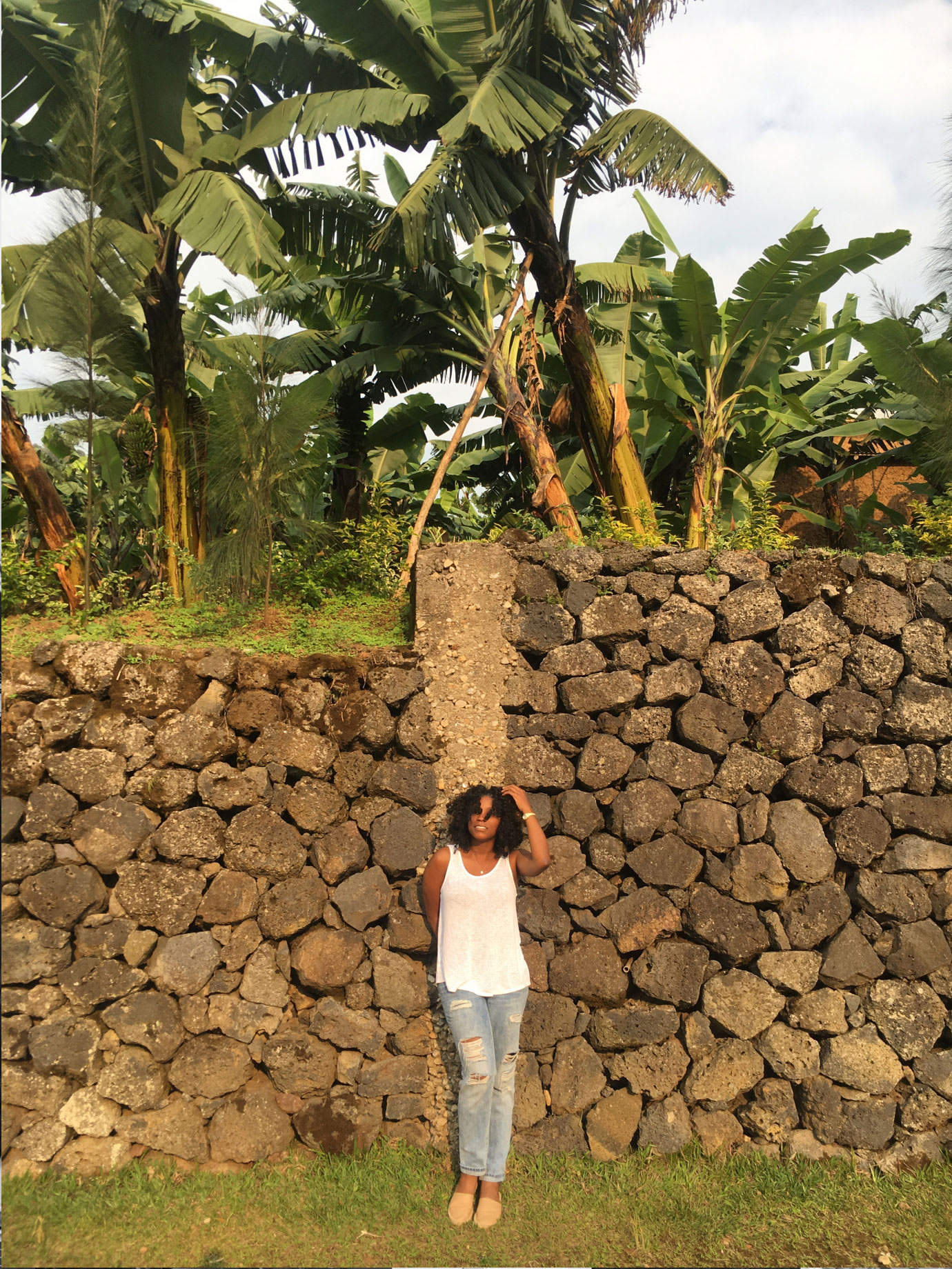 A woman standing in front of a stone wall.