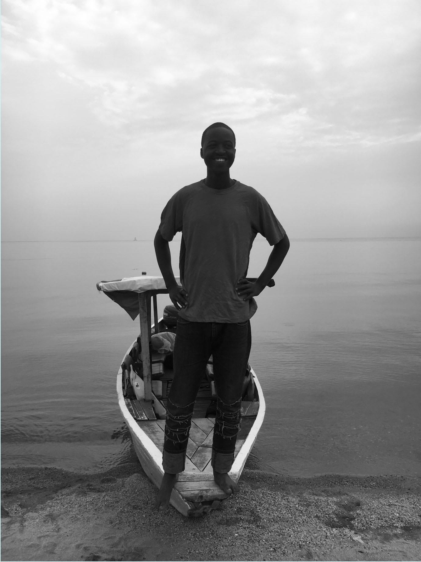 A man standing on a canoe on a beach.