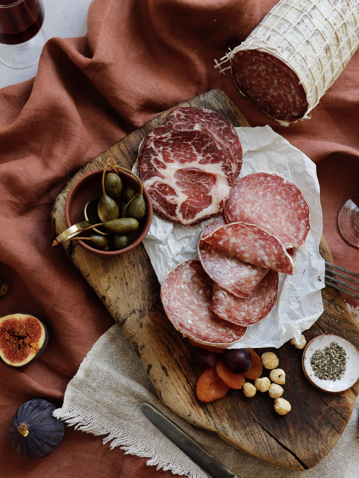 Cold meats and sausage on a pink cloth.