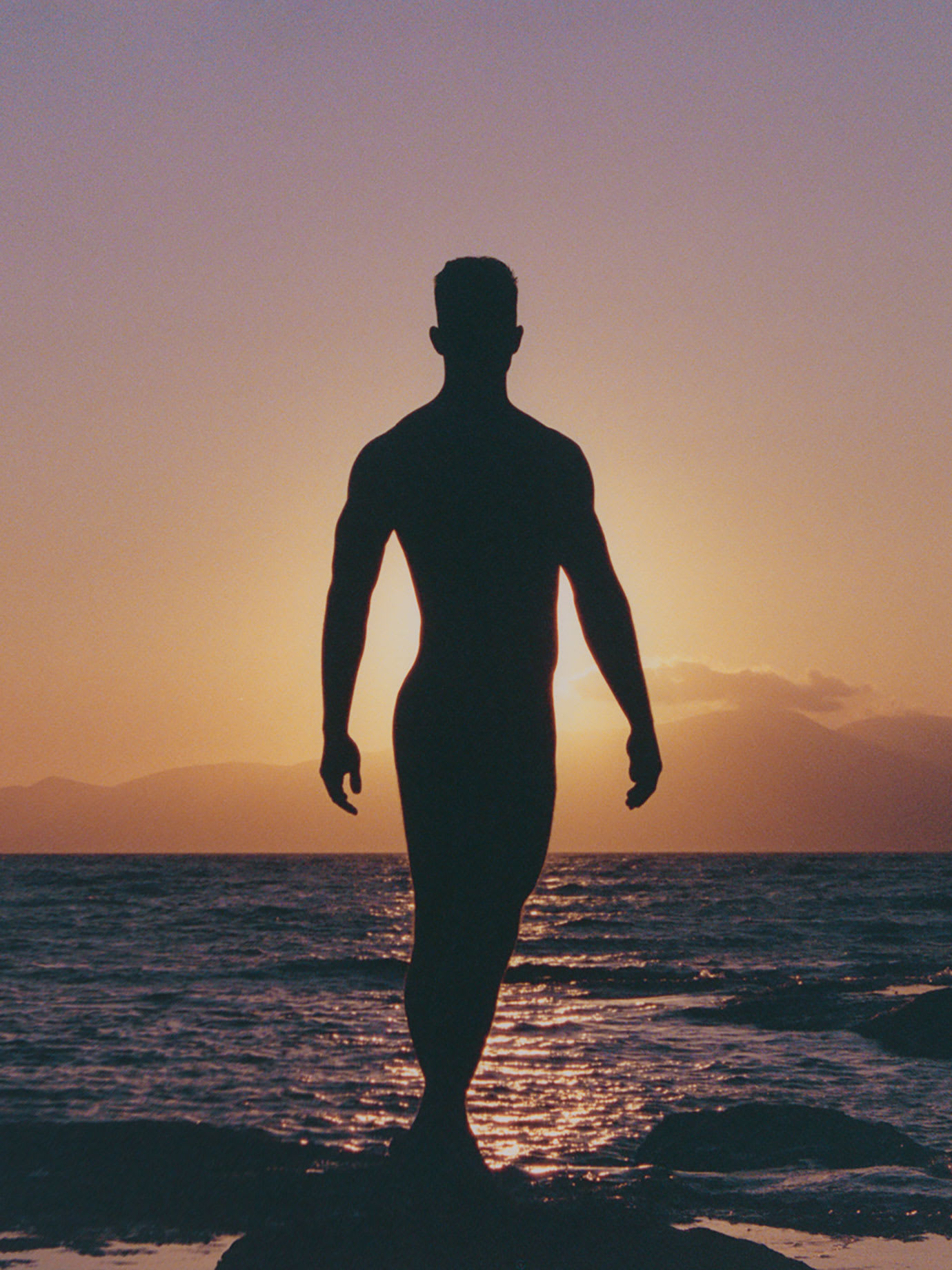 A man in silhouette by the sea.