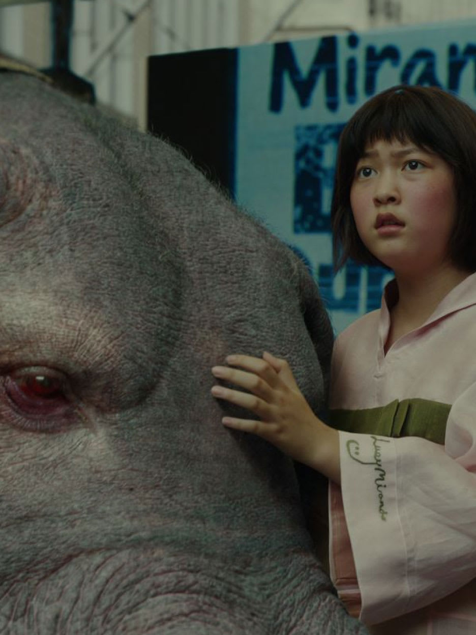A young girl with her hand on a giant animal.