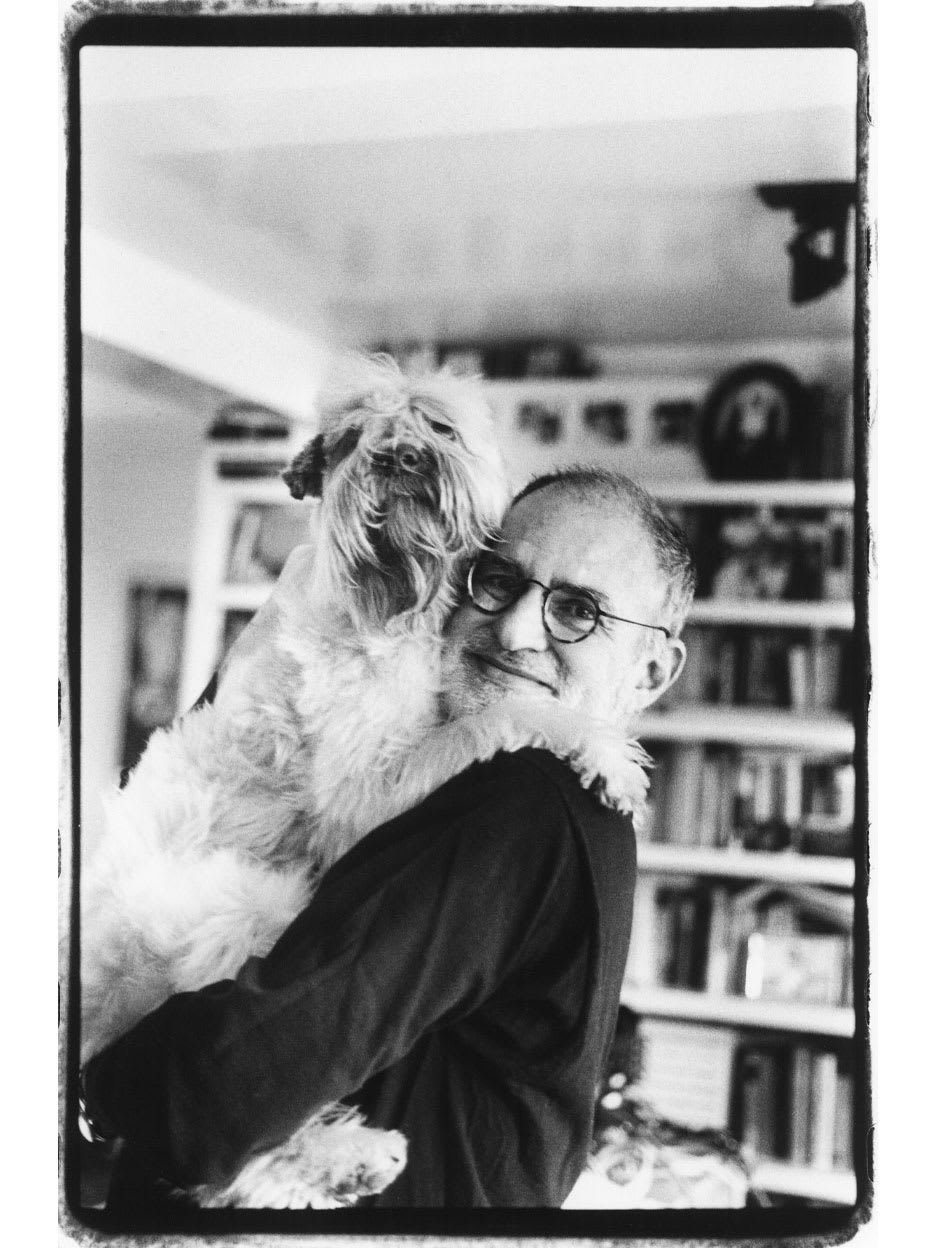 A man smiling while holding his dog.