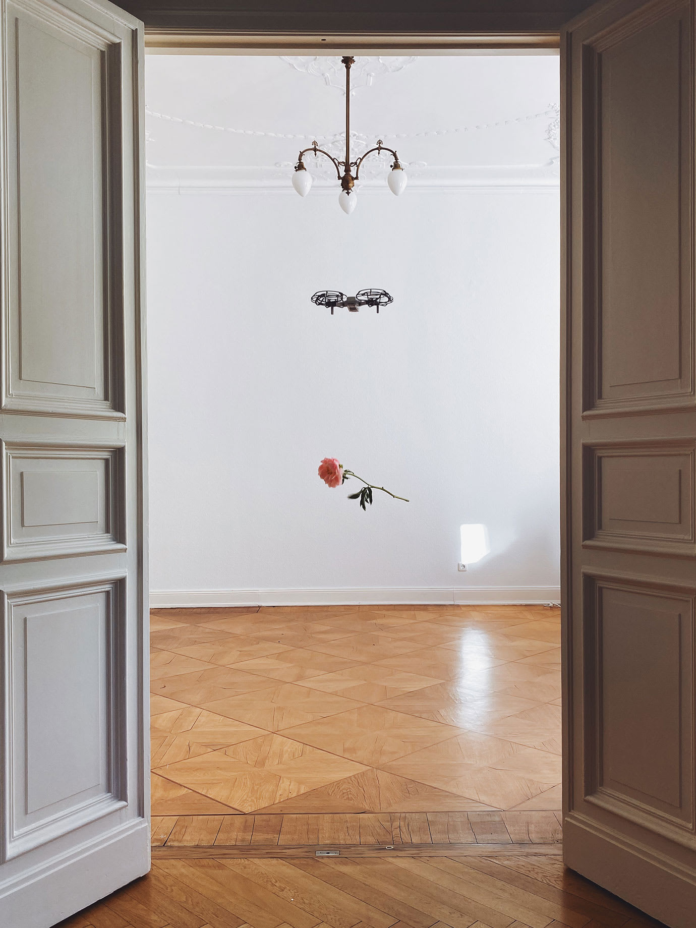 A flower hanging from a drone flying in a hallway.