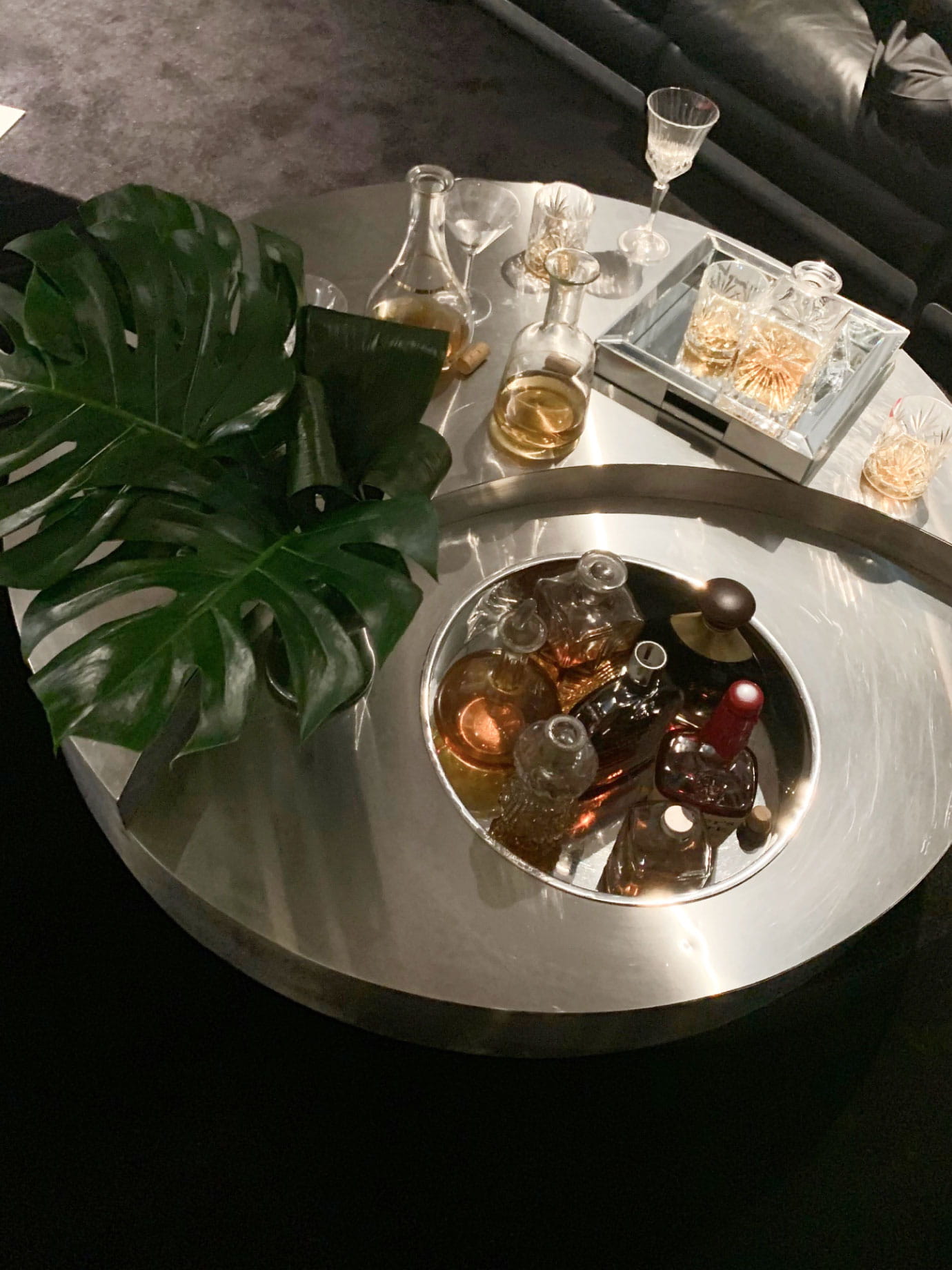 Cocktails in small bottles next to a plant.