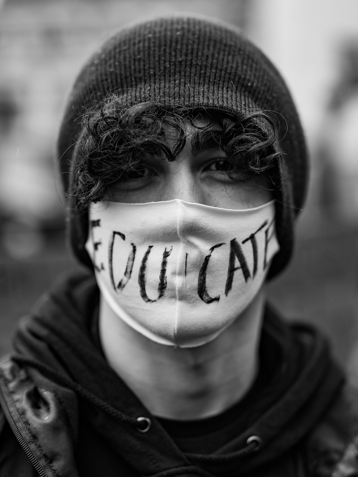 A young man wearing a face mask with the word educate written on it.