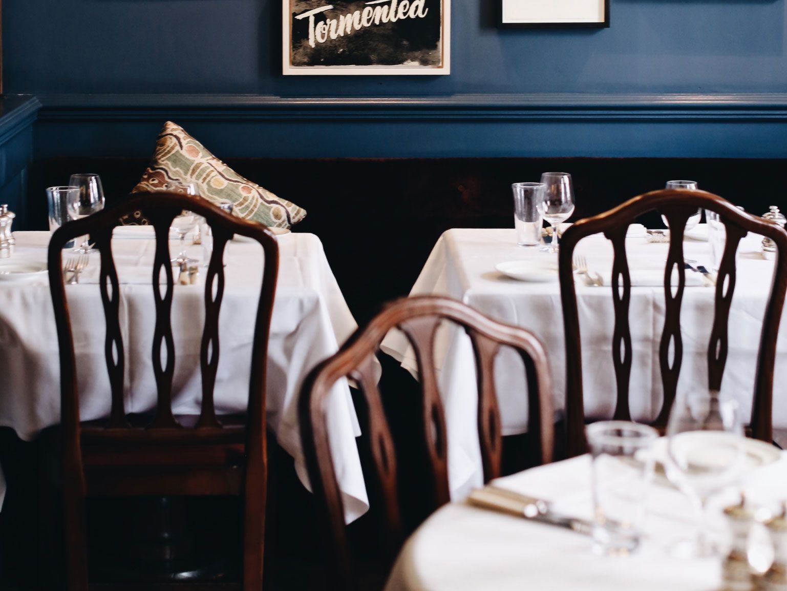 Three tables laid for dinner in a blue room.