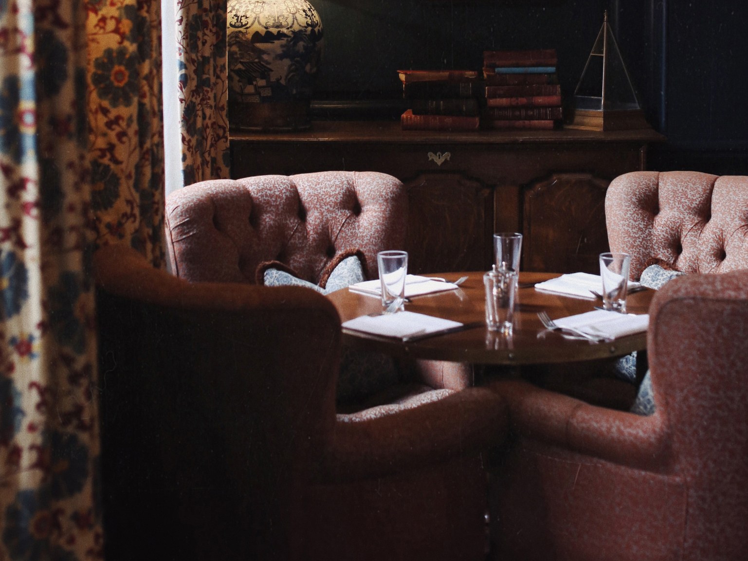 A table laid out for lunch with chairs around it in the corner of a room.