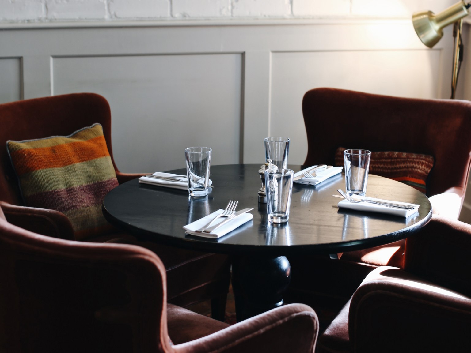 A relaxed dining table surrounded by soft chairs laid out for dinner.