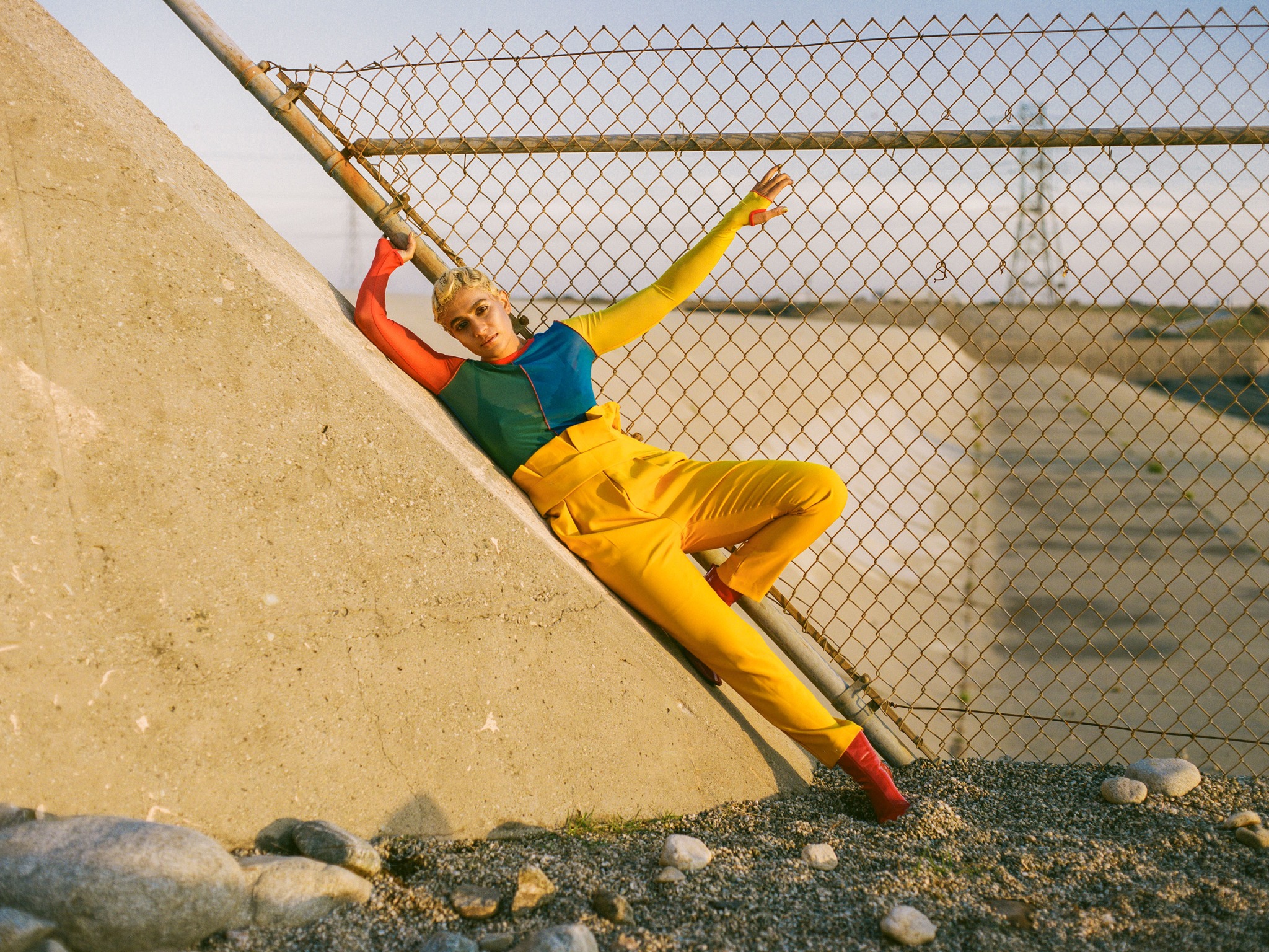 A woman wearing colourful clothing leaning against a concrete wall.
