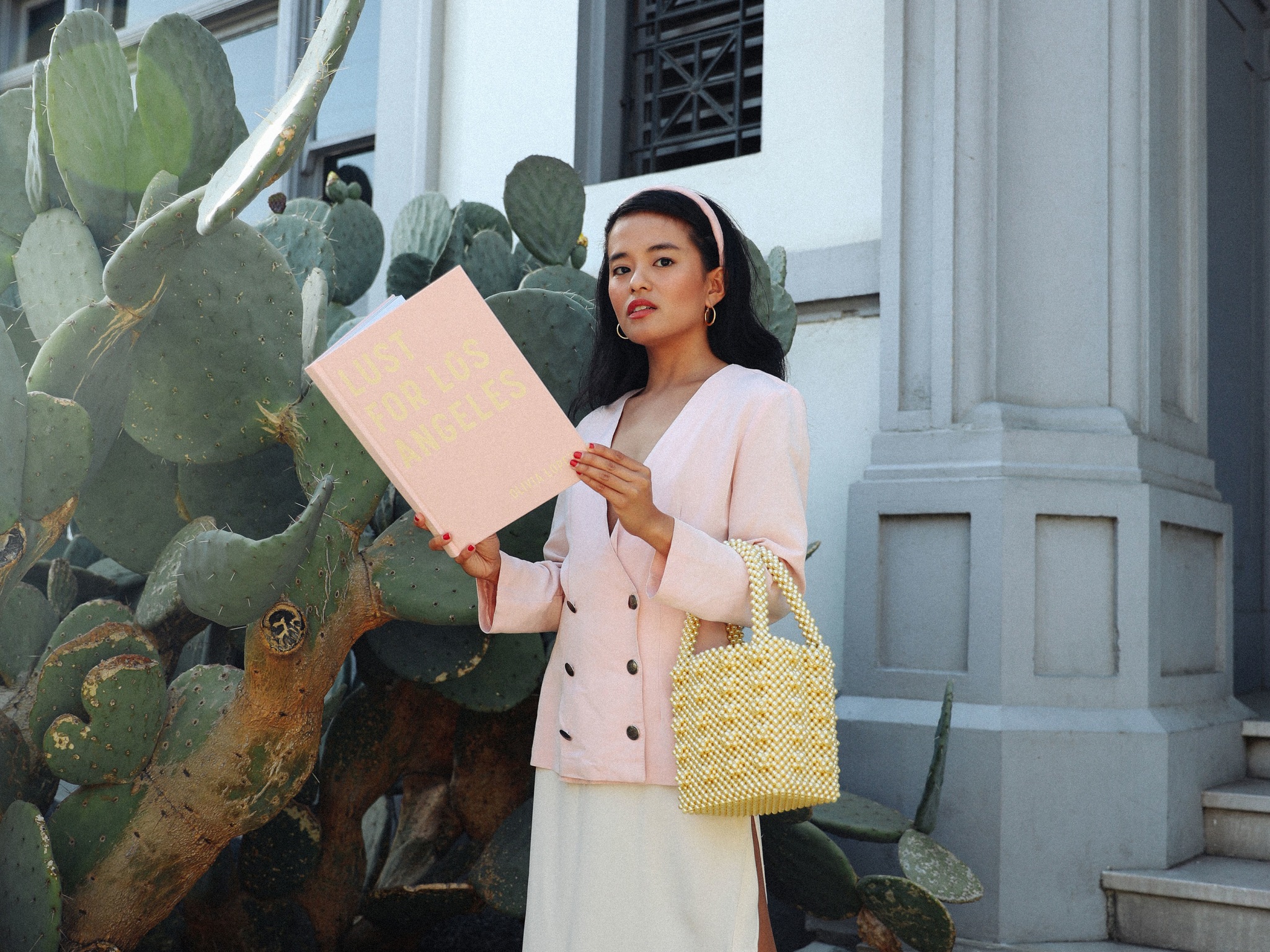 A woman holding a book in front of a white building.
