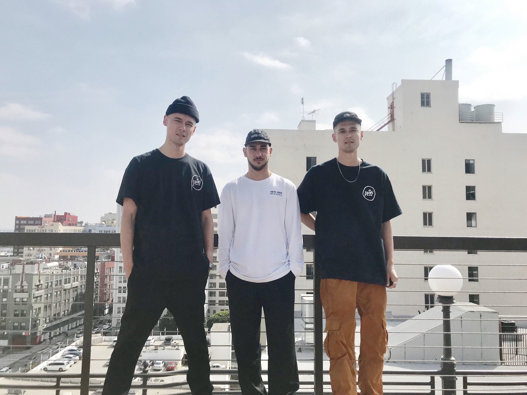 Three men standing on a roof in a city.