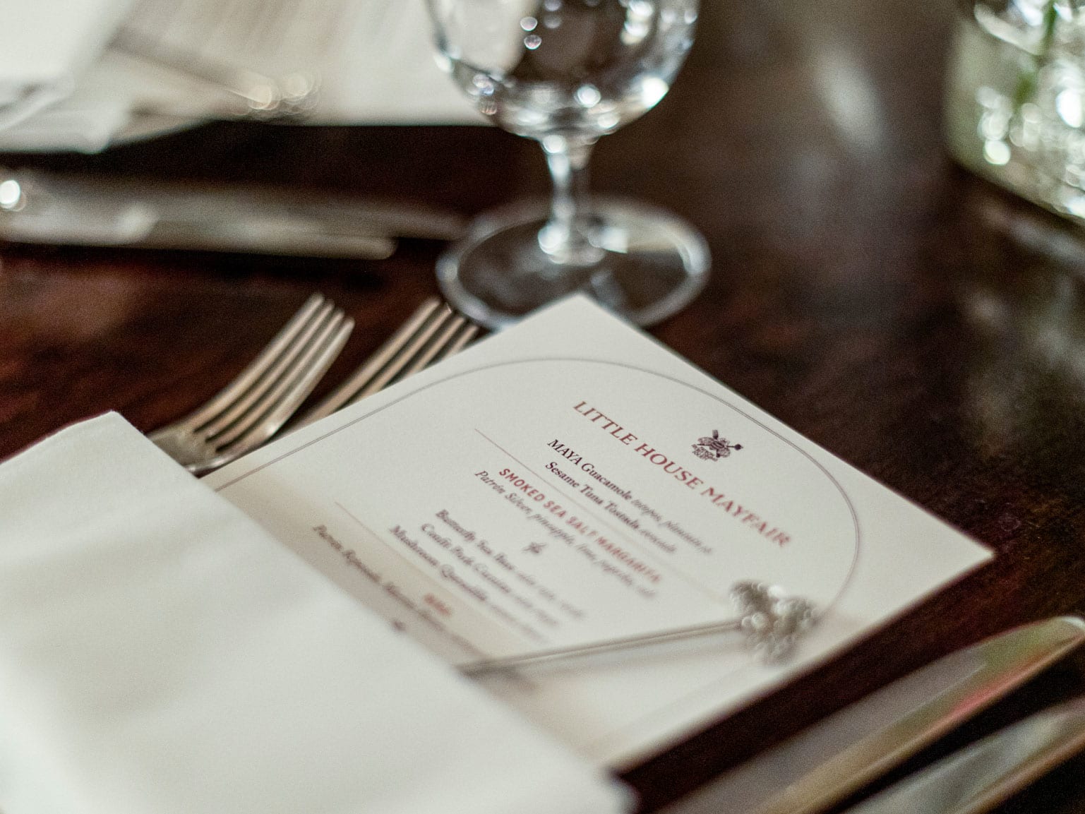 A close up of a laid dining table with tailored menus tucked into serviettes.