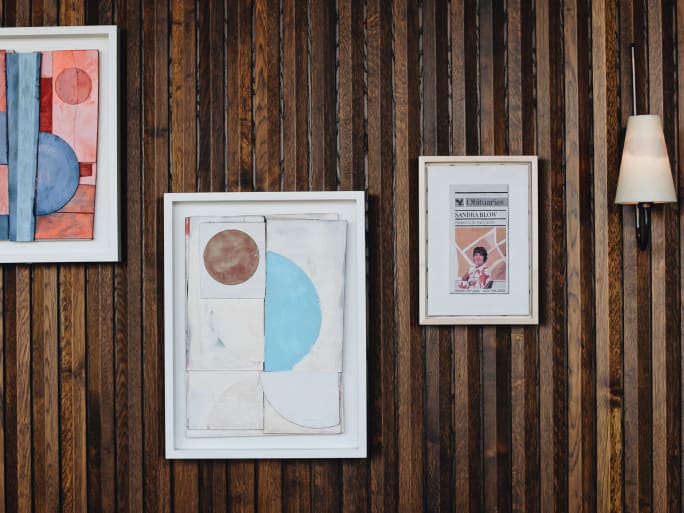 Three artworks on a wooden wall.