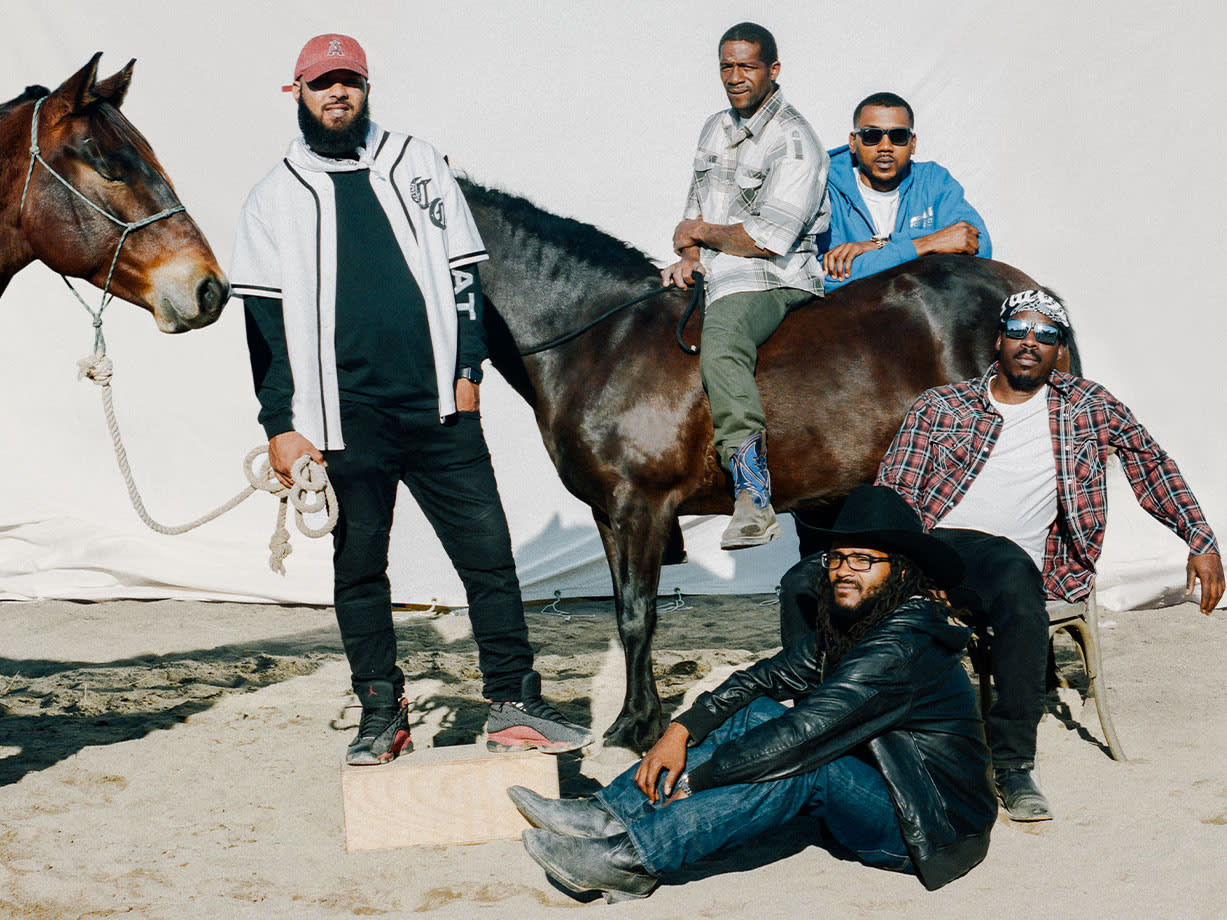 group of men standing with horses by screen with one riding a horse