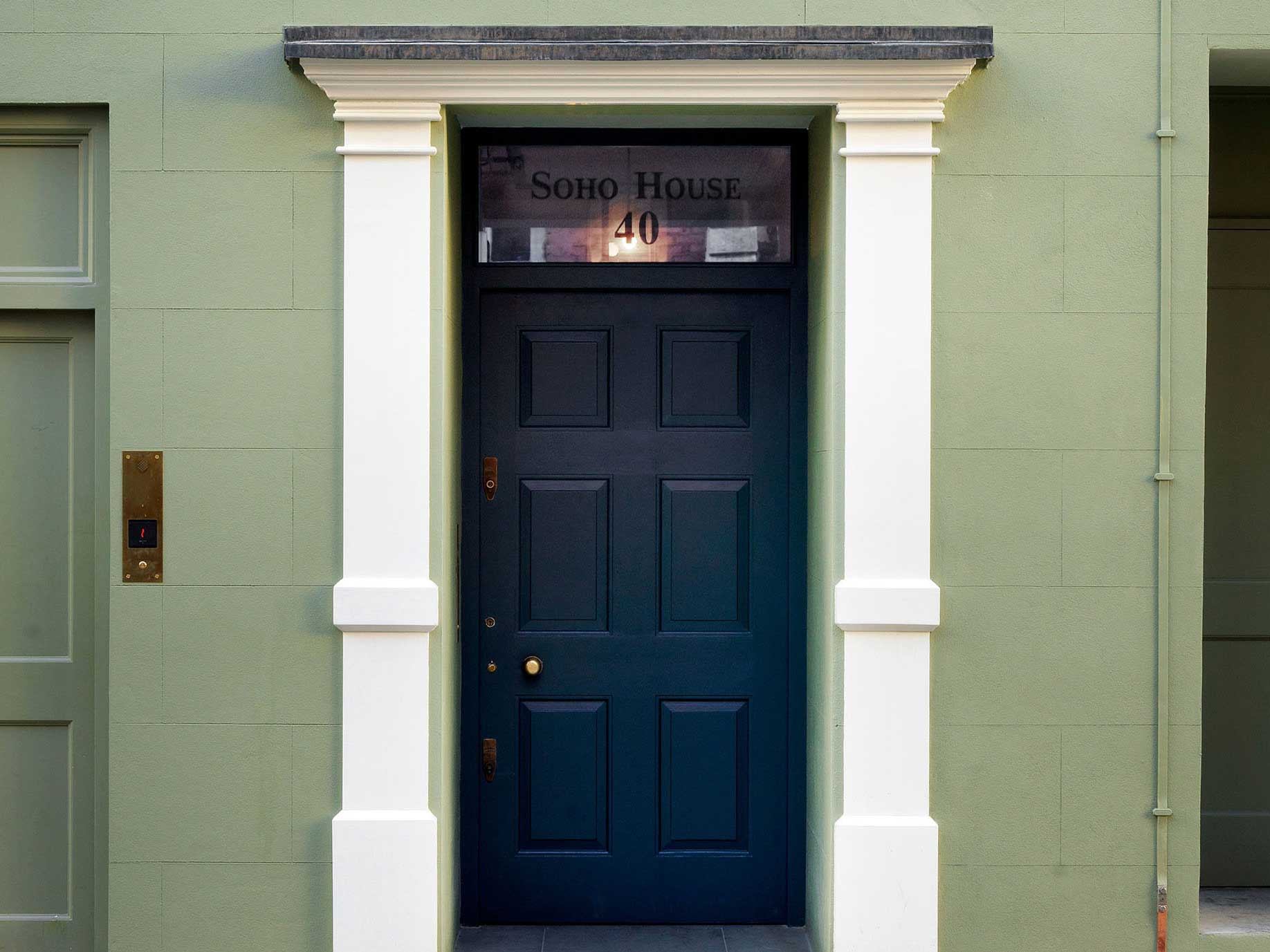 Blue front door on a green wall