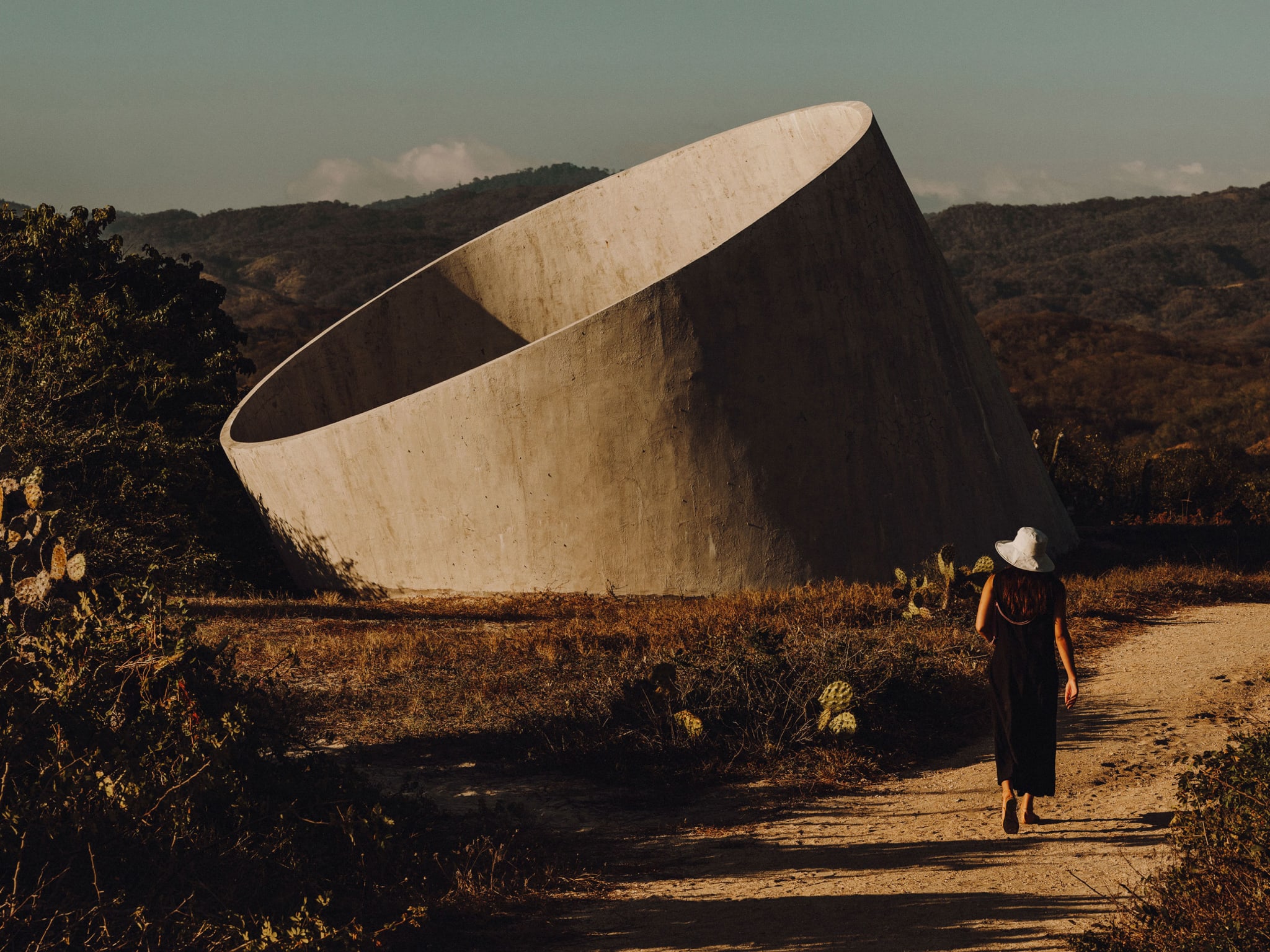 A woman walking towards a circular concrete structure.