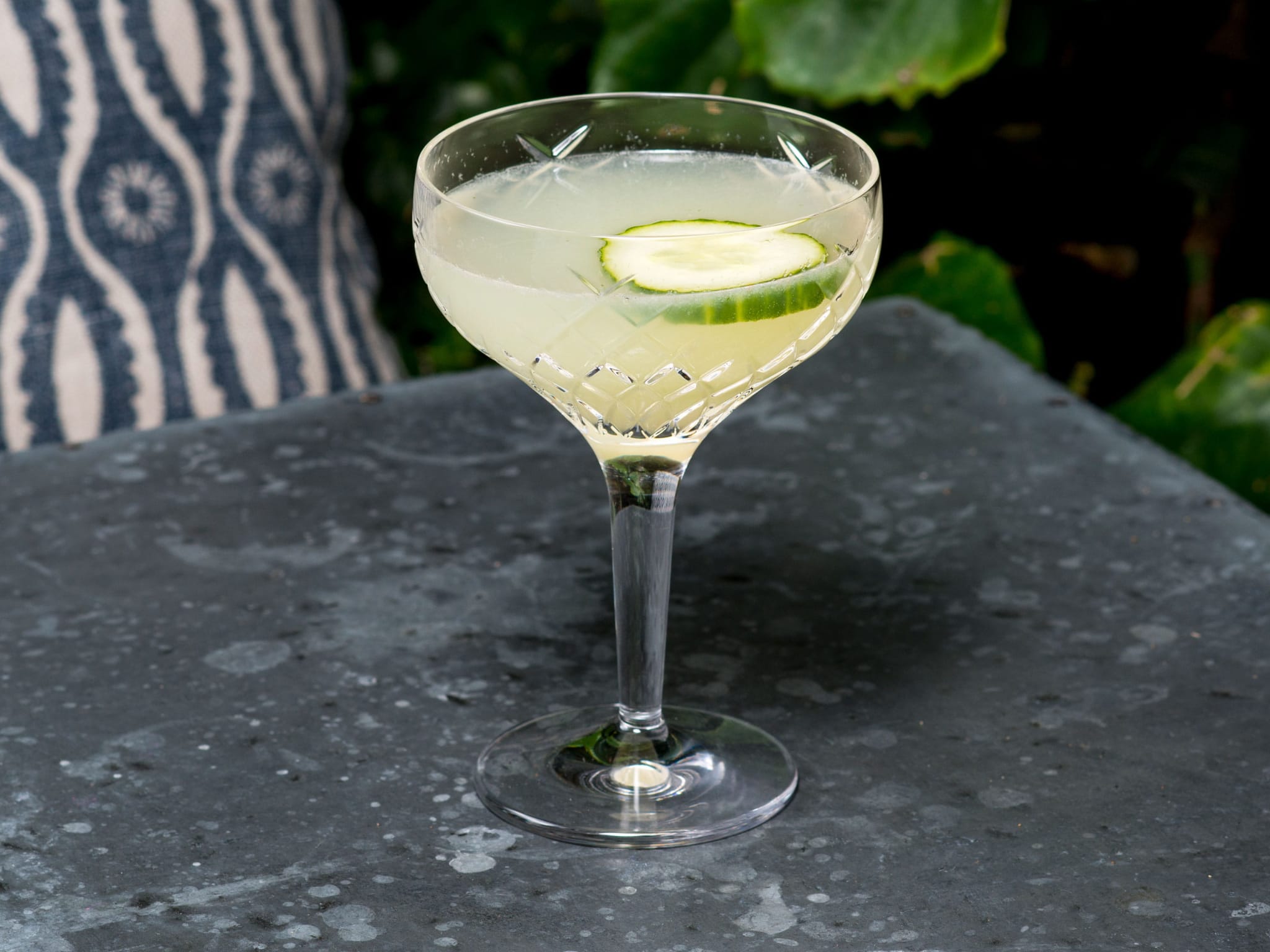 A cocktail with a slice of cucumber in it.
