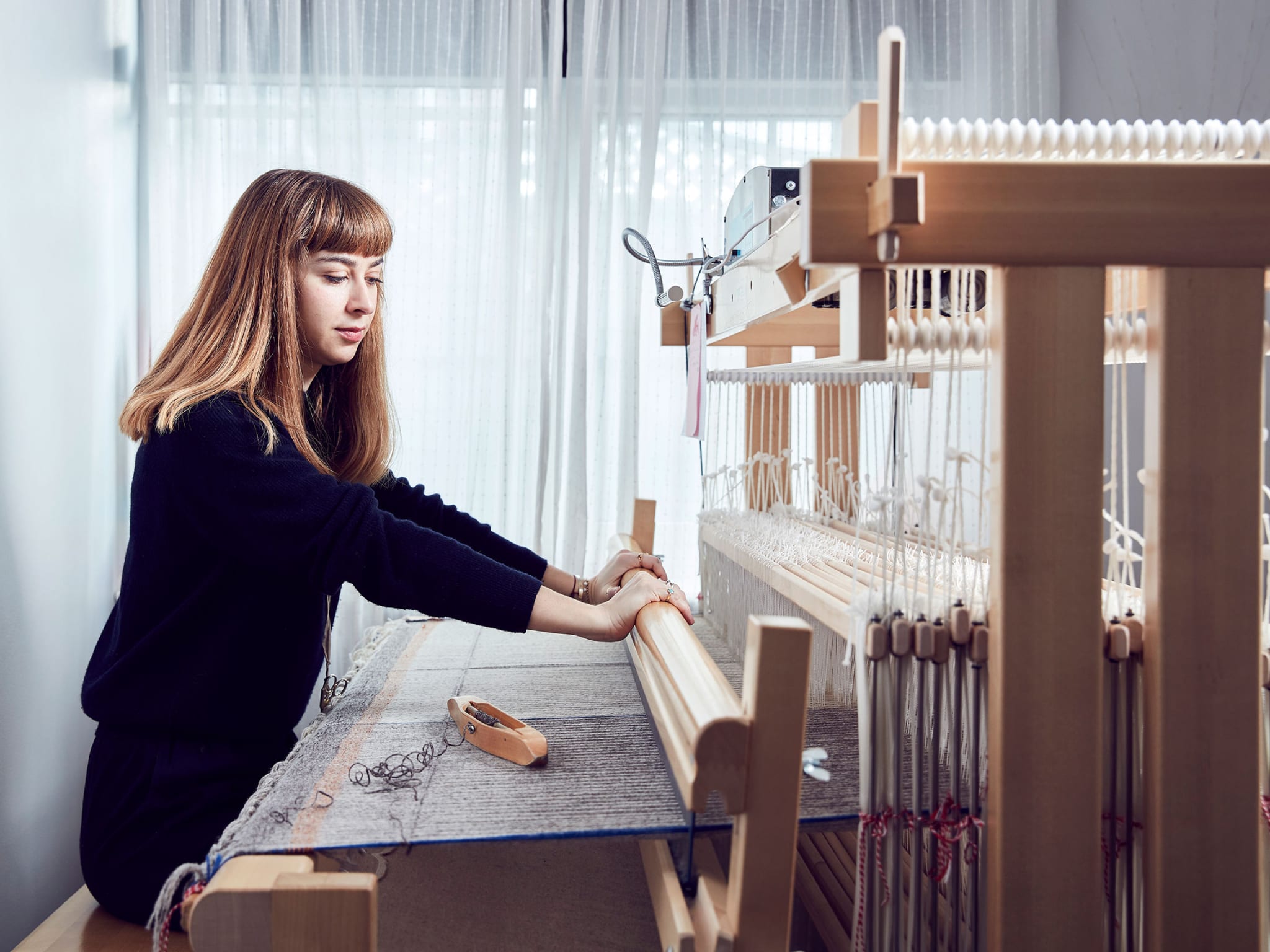 a woman weaving at a loom