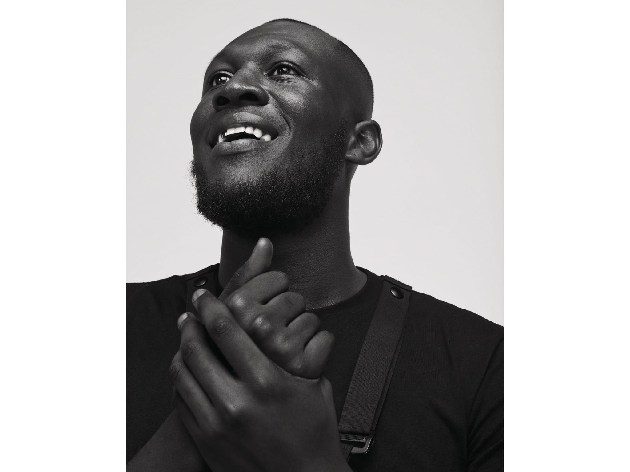 A man smiling while holding his hands.