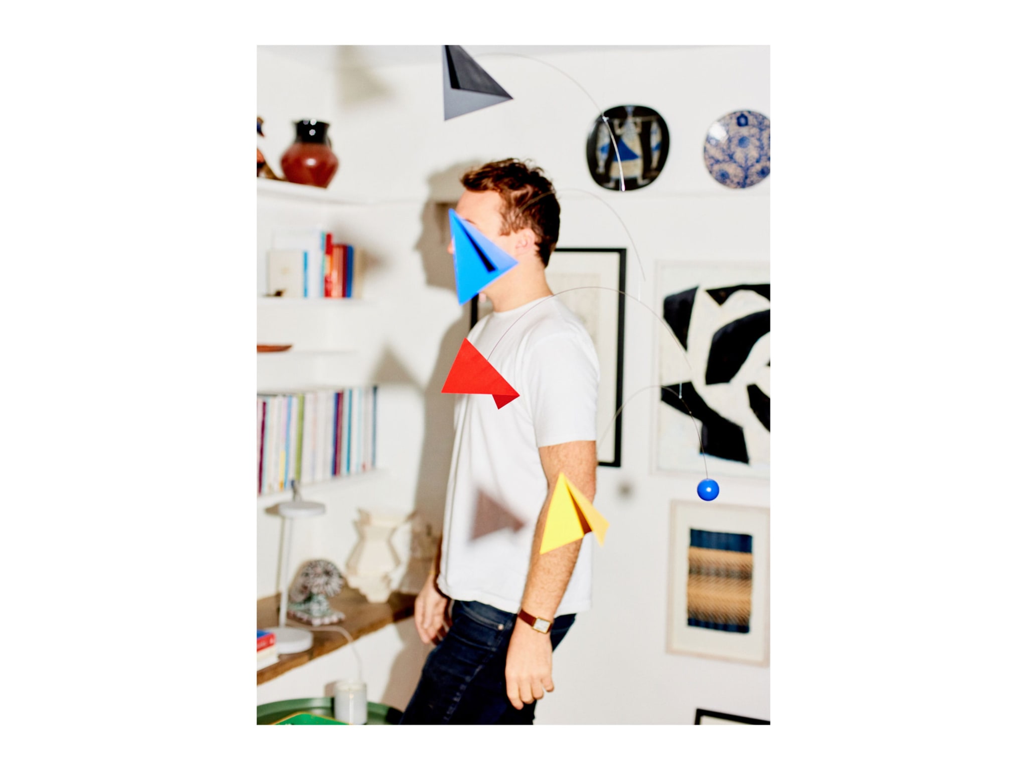 A man standing behind a multi-coloured mobile.