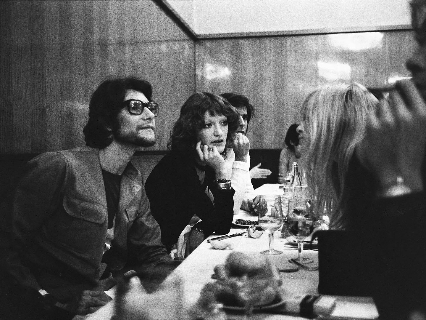 A man and a woman in vintage clothing chatting over a restaurant table to other people.