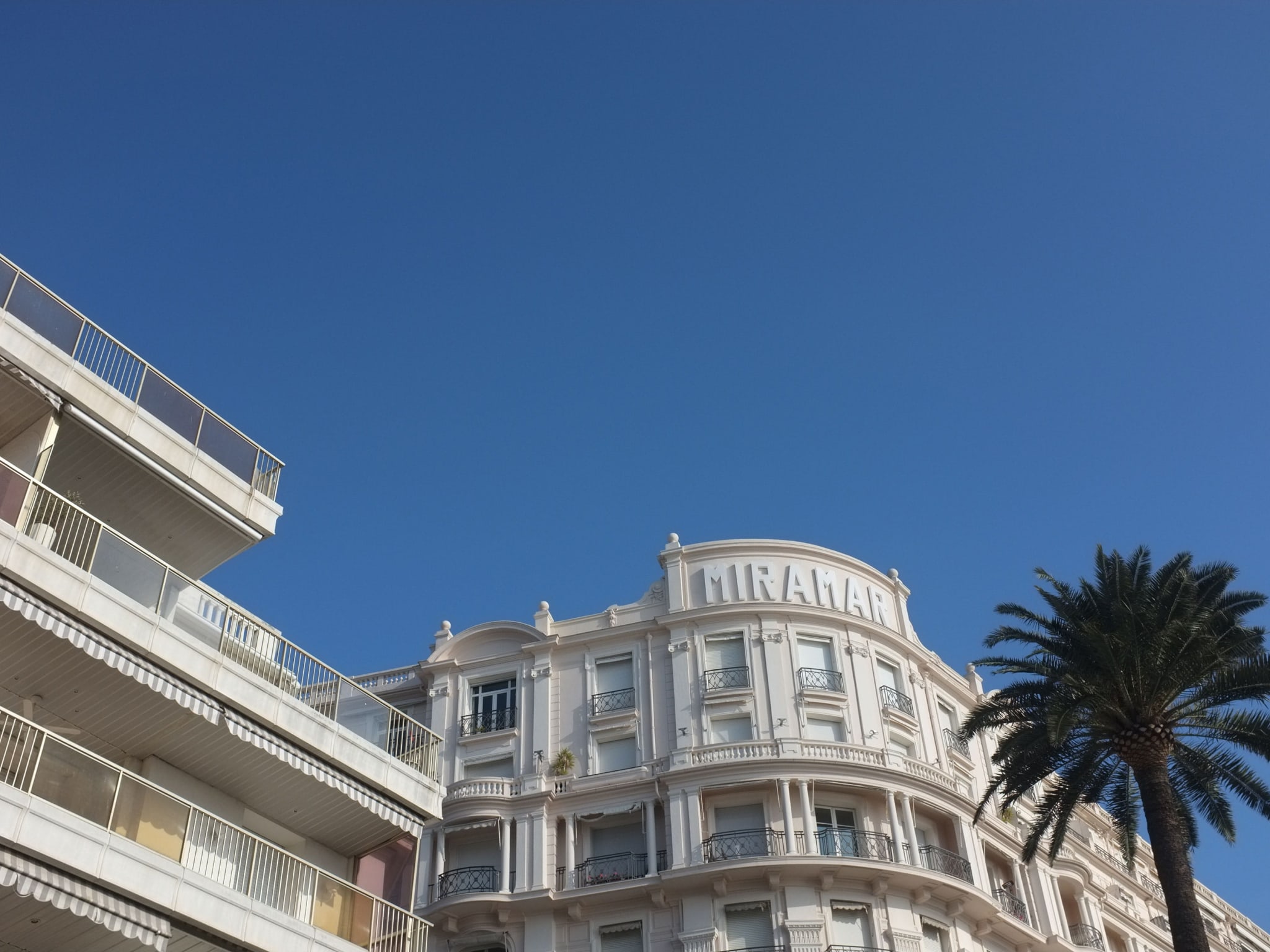 The exterior of a white building and blue sky above it.