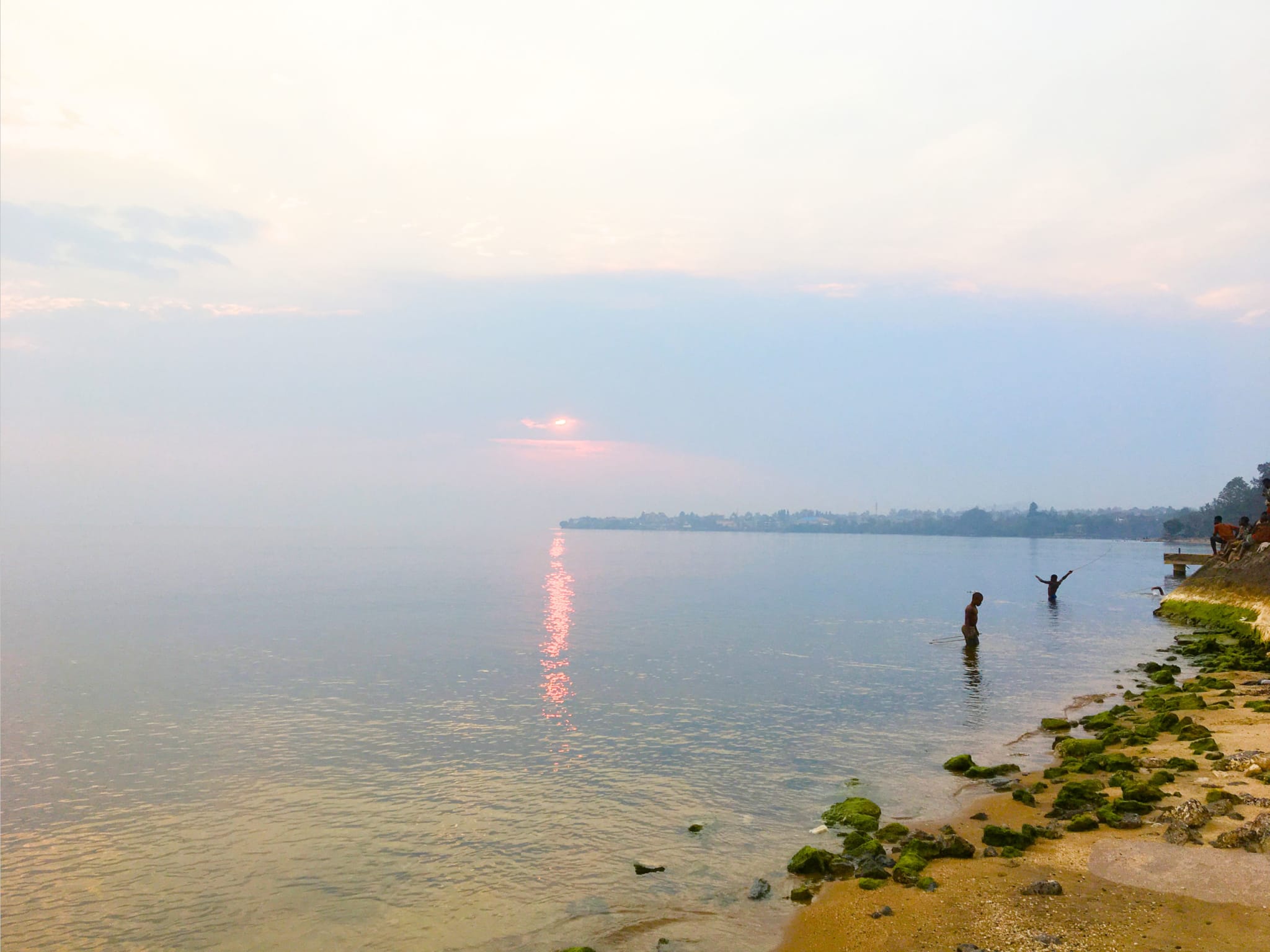 Two people playing in a lake at sunset.