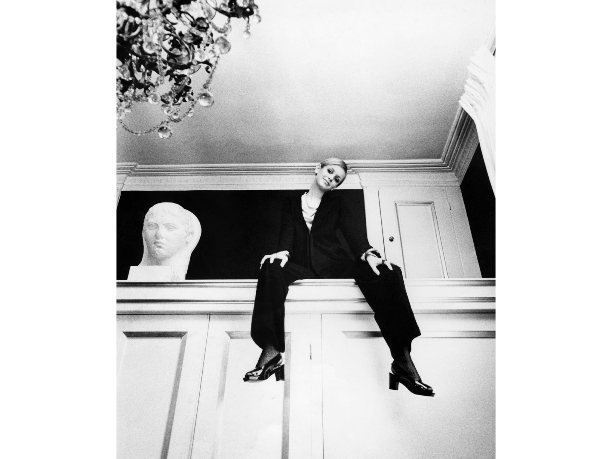 A woman sitting on top of a white wardrobe.