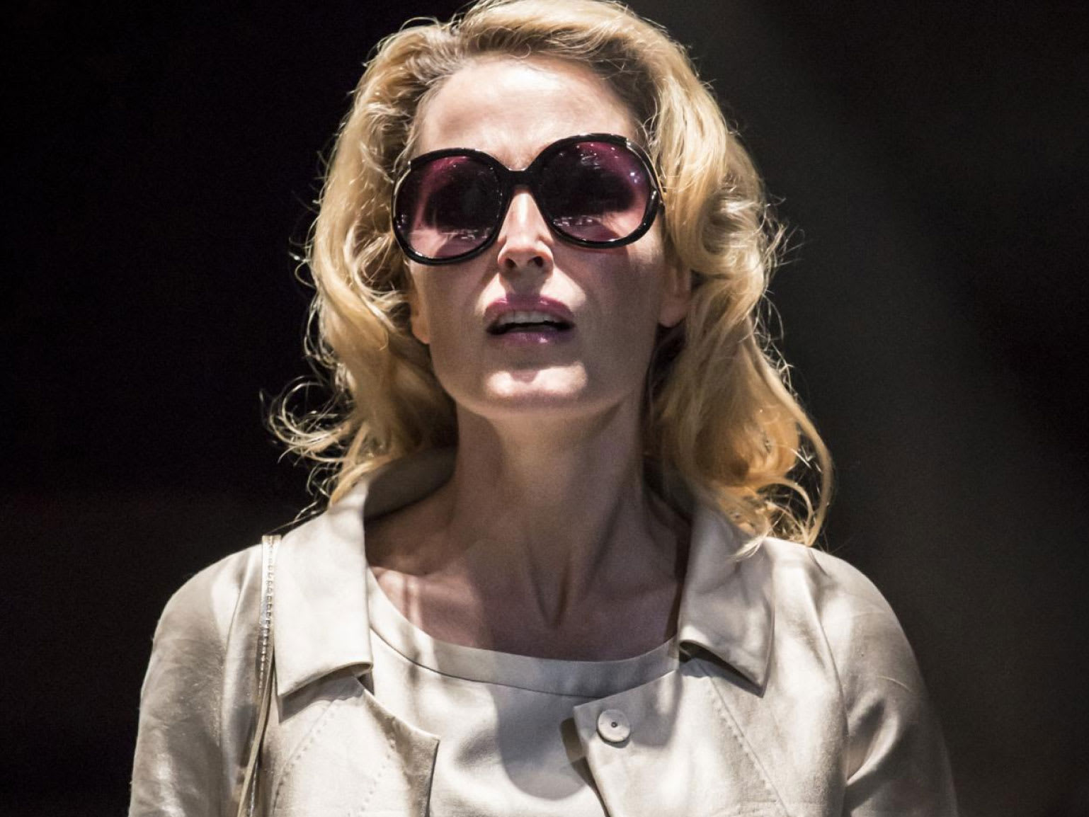 A woman with a spotlight on her wearing sunglasses.
