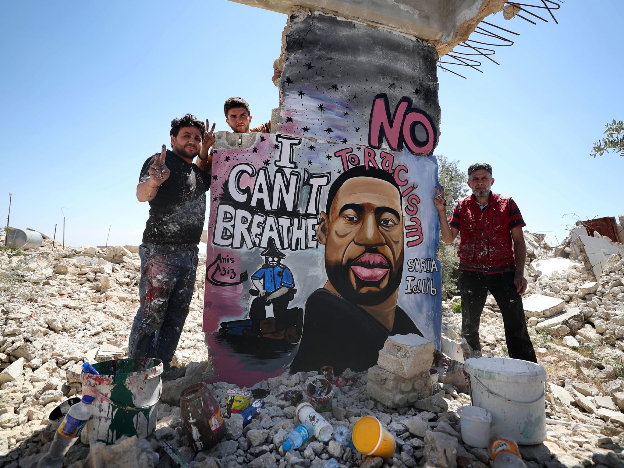 A mural in a bombsite with three men standing around it.