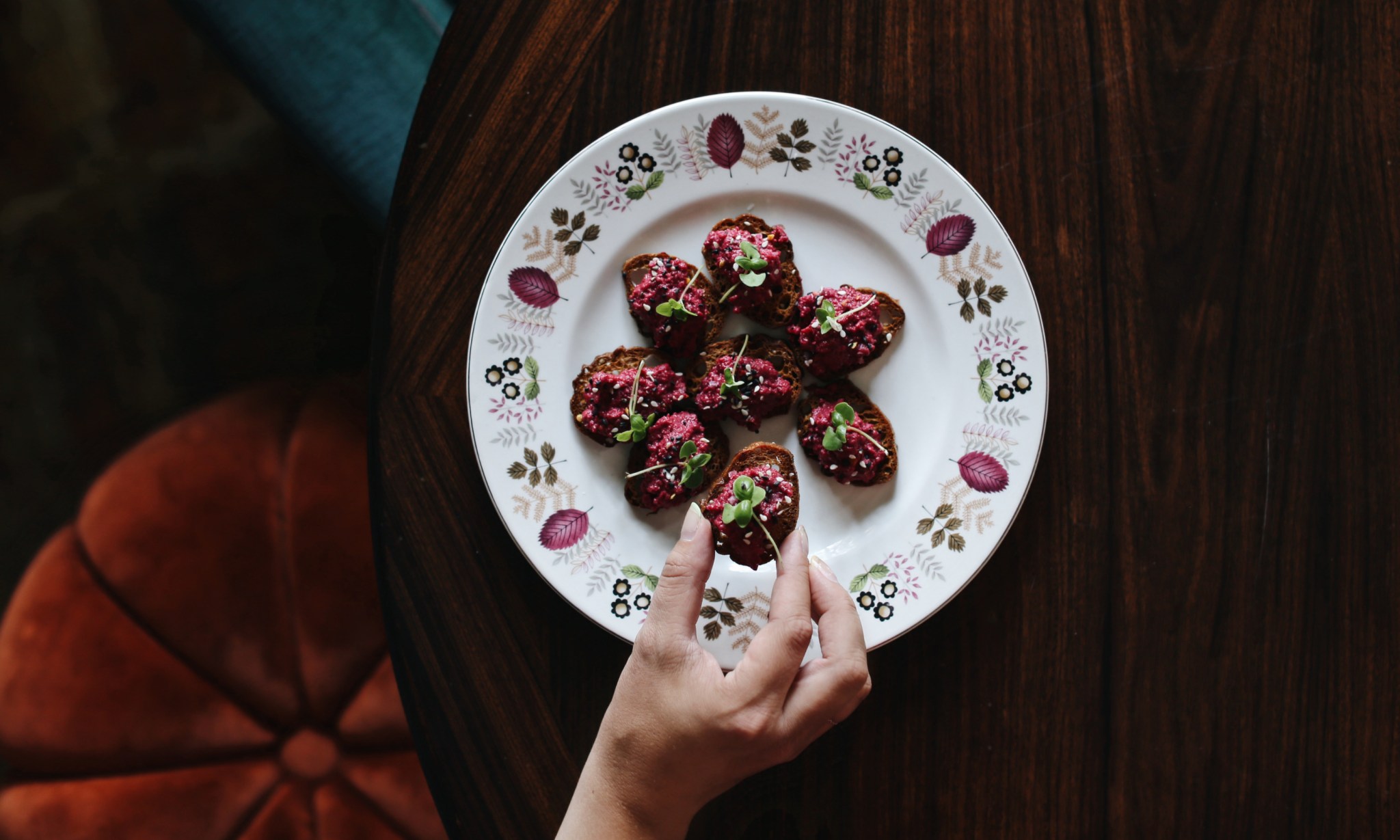 A hand picks an item of food from a plate.
