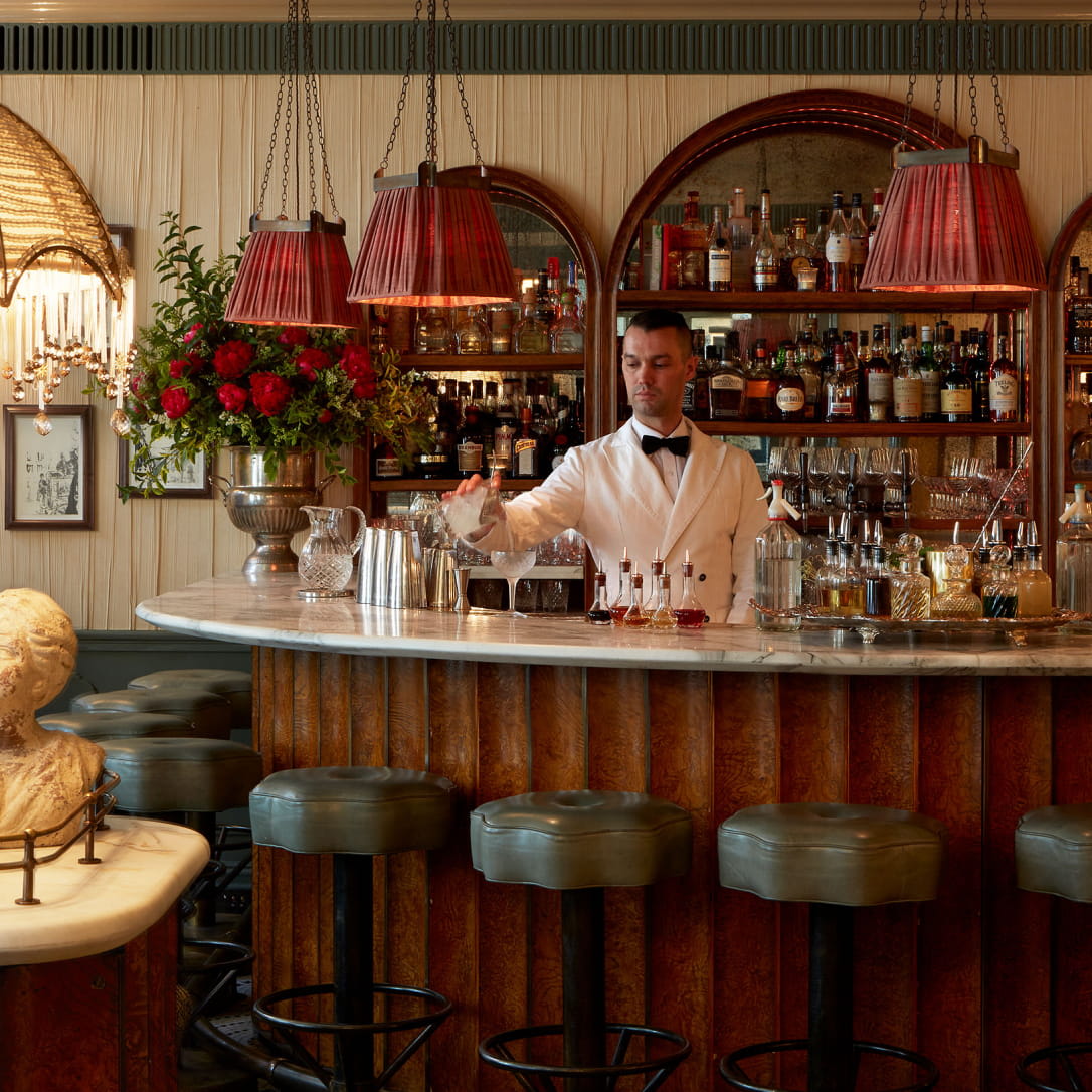 A barman pours champagne on a marbled bar.