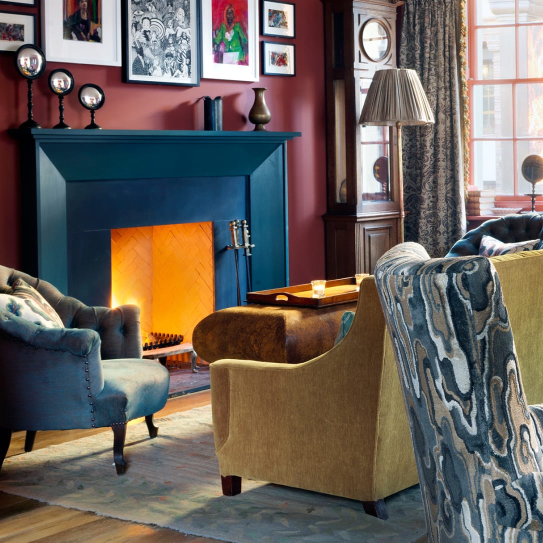 A burning fireplace with a sofa in front of it.