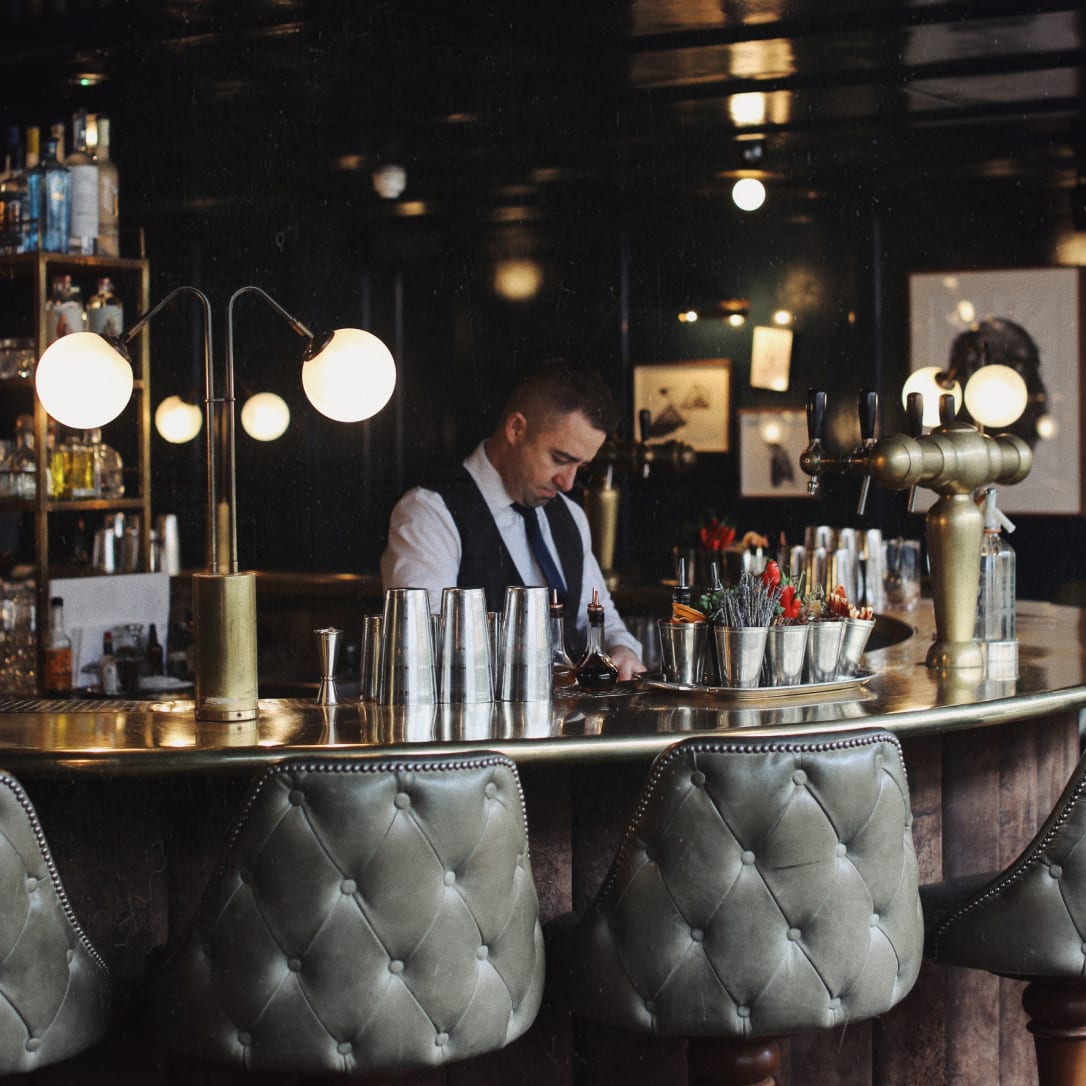 Shelves behind a bar with glasses and alcohol bottles on it.